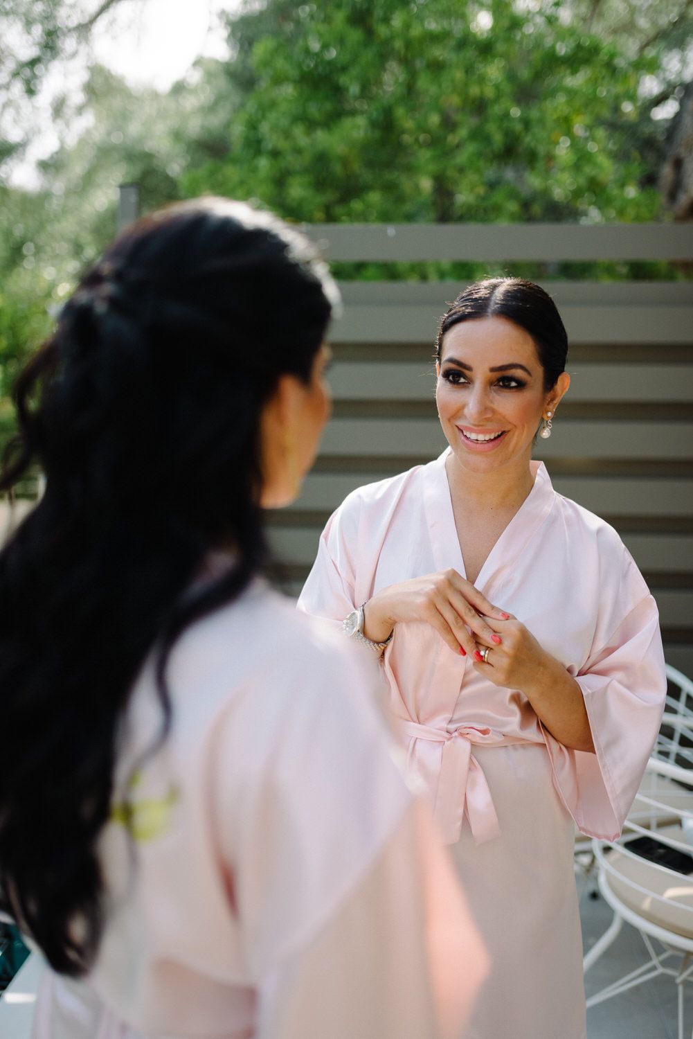 Wedding party member in pink silk robe smiling during preparation.