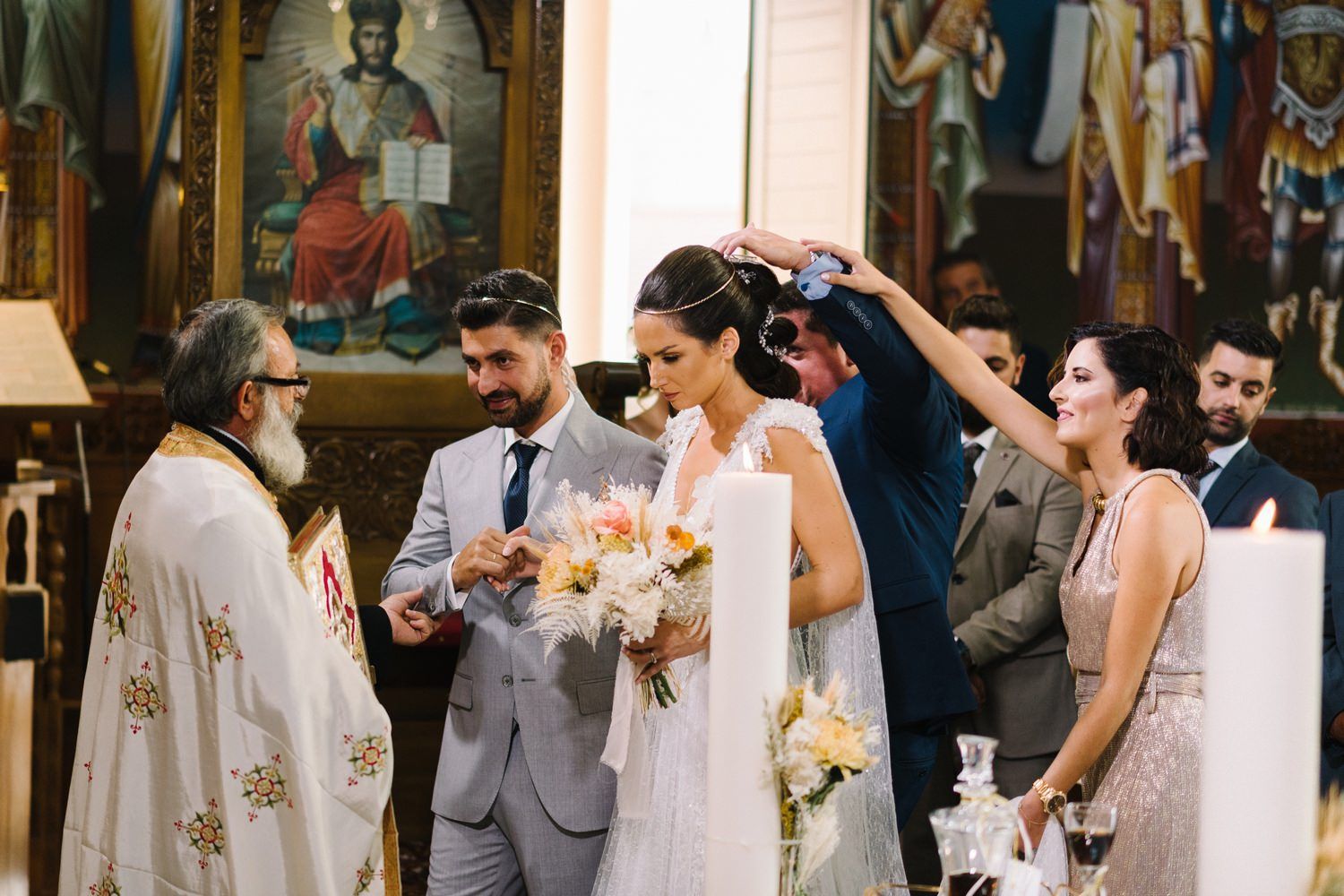 Guests observe as an Orthodox priest performs a traditional wedding ceremony in front of religious icons.