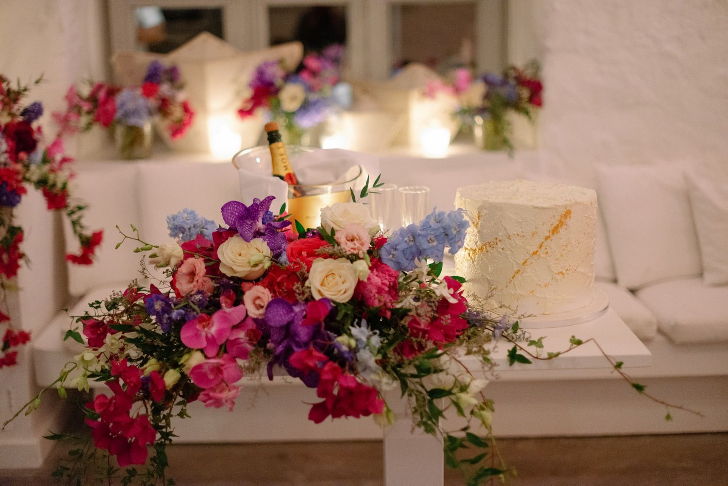 Vibrant floral arrangement with pink, purple and white flowers decorates a white table at an elegant event setting.