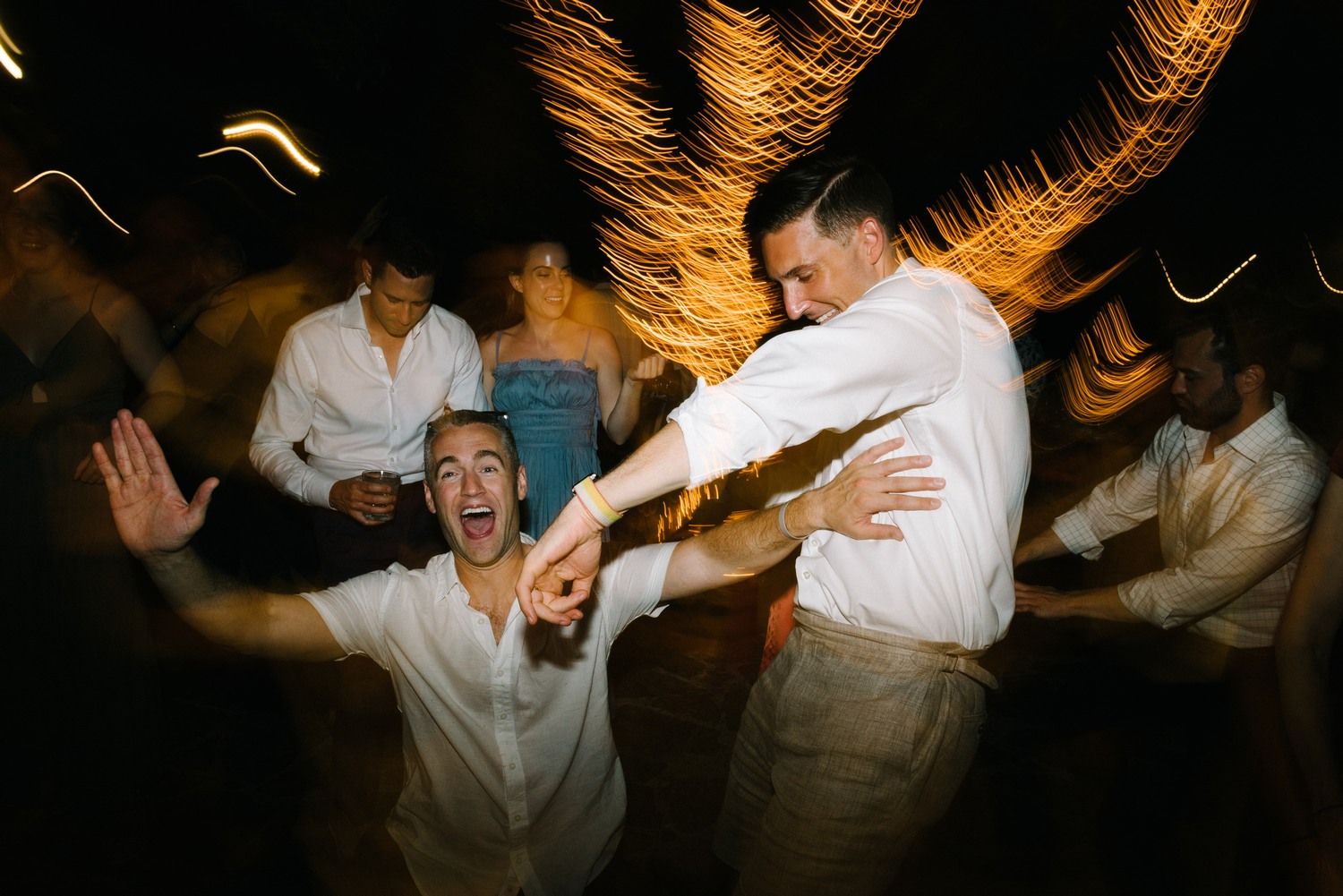 Dynamic nighttime party scene with guests dancing and celebrating with motion blur effects.