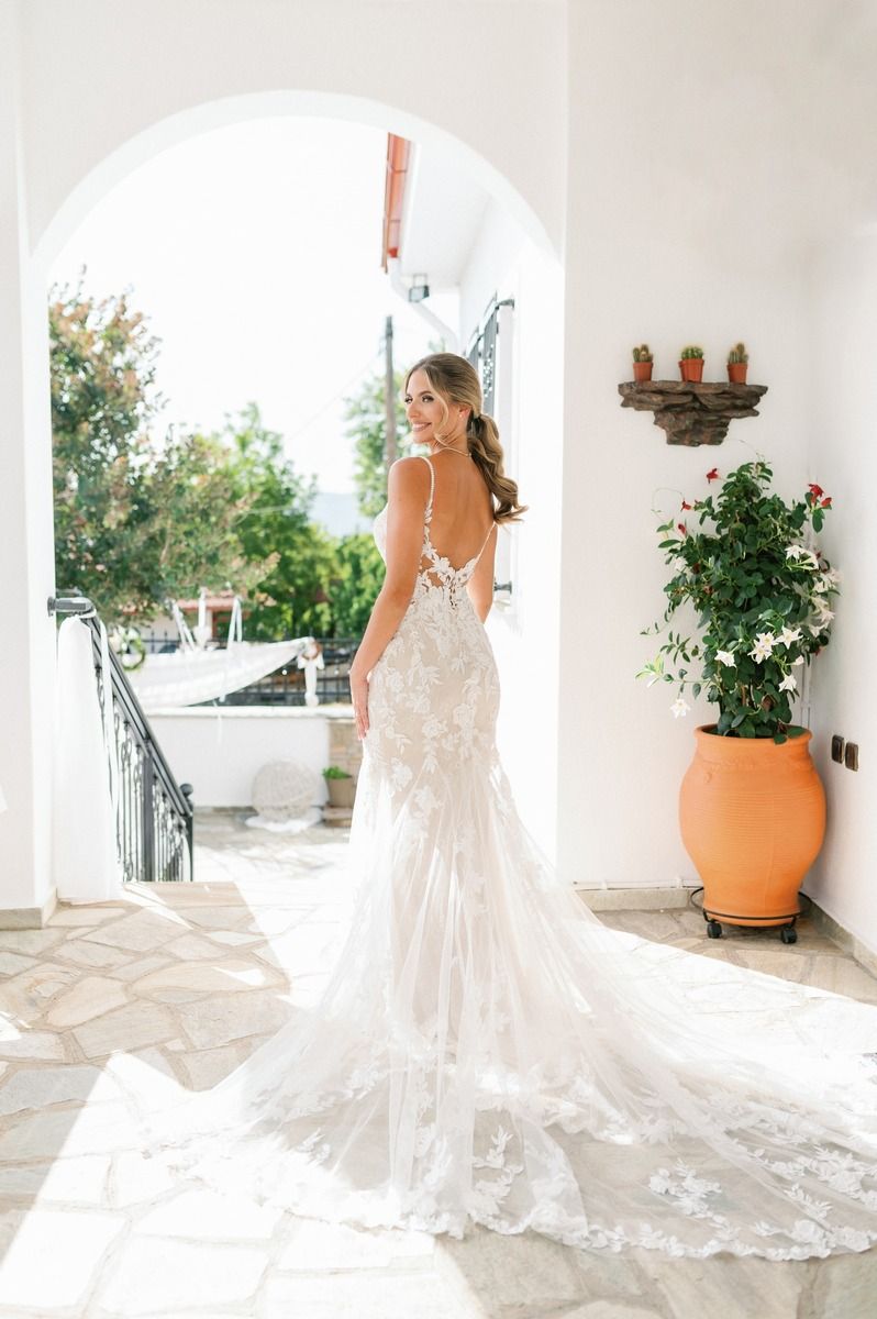 A stunning bridal portrait showing the full train of a lace wedding gown in an arched doorway.