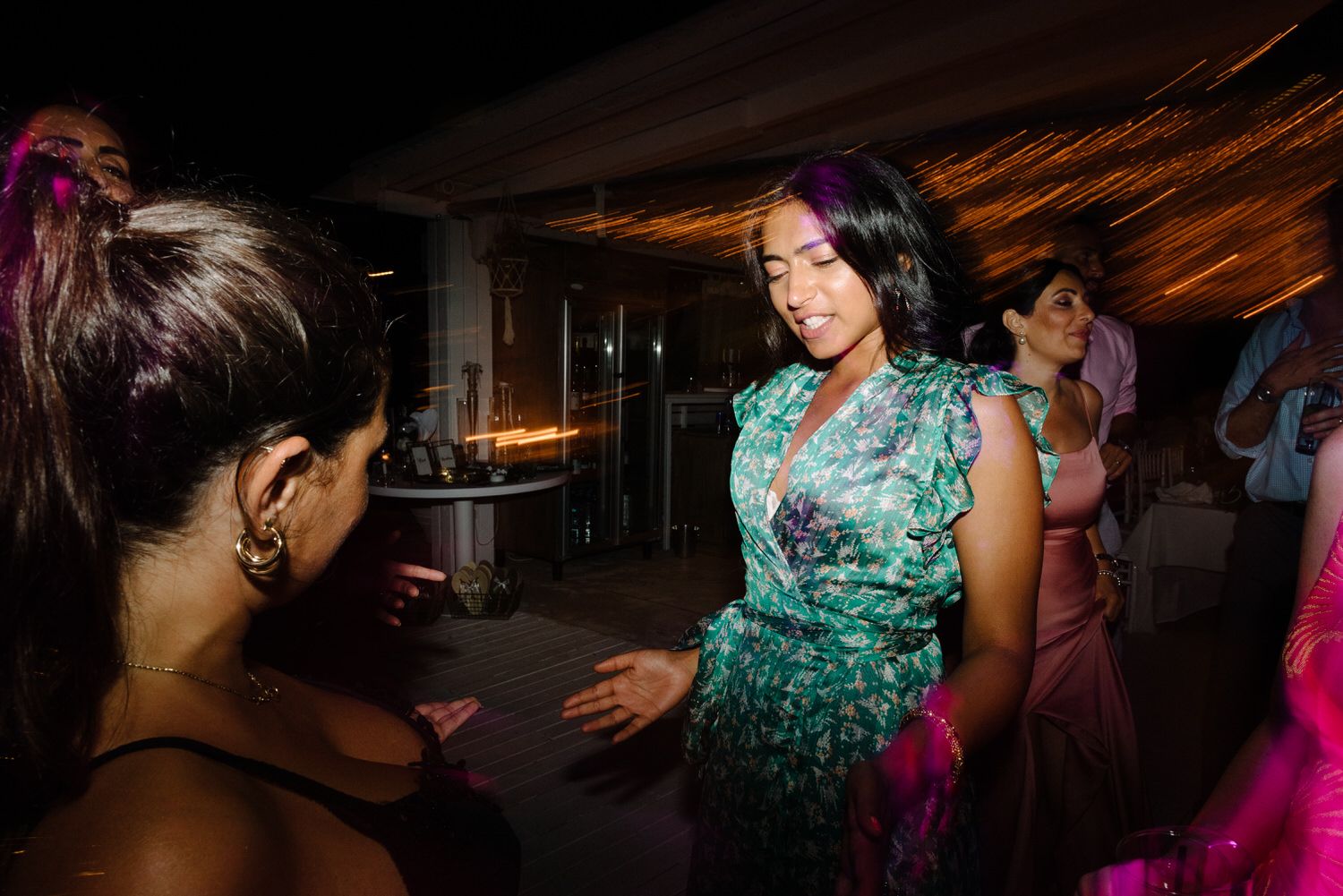 Reception guests dancing and celebrating in formal attire under warm lighting.