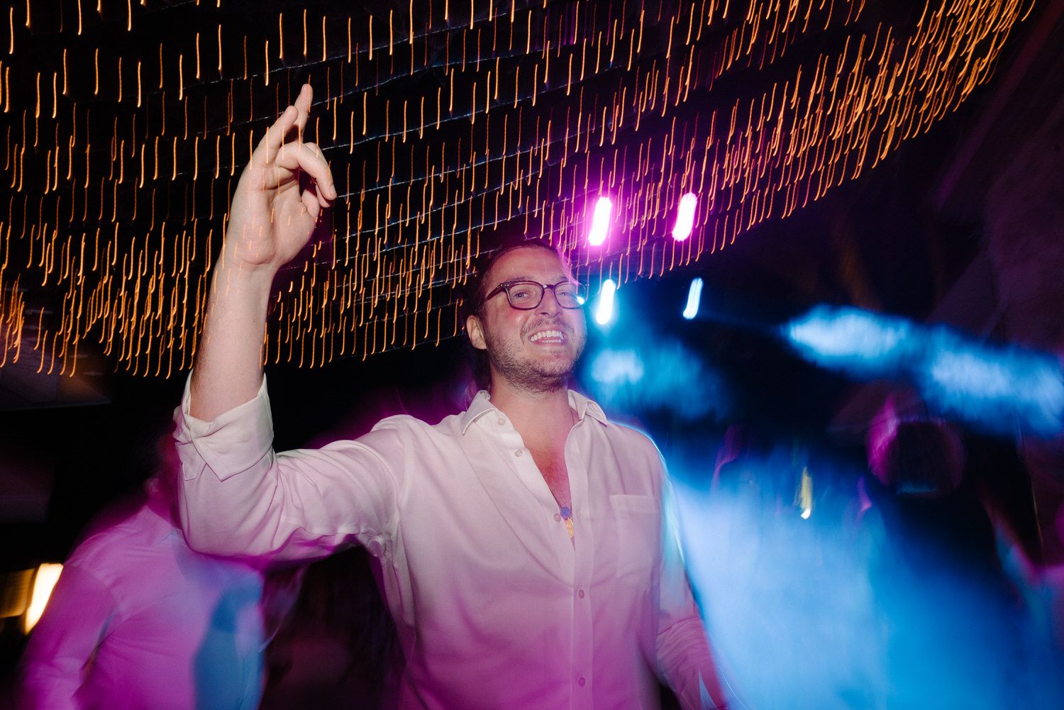 Energetic dance floor moment captured with atmospheric lighting and smoke effects.