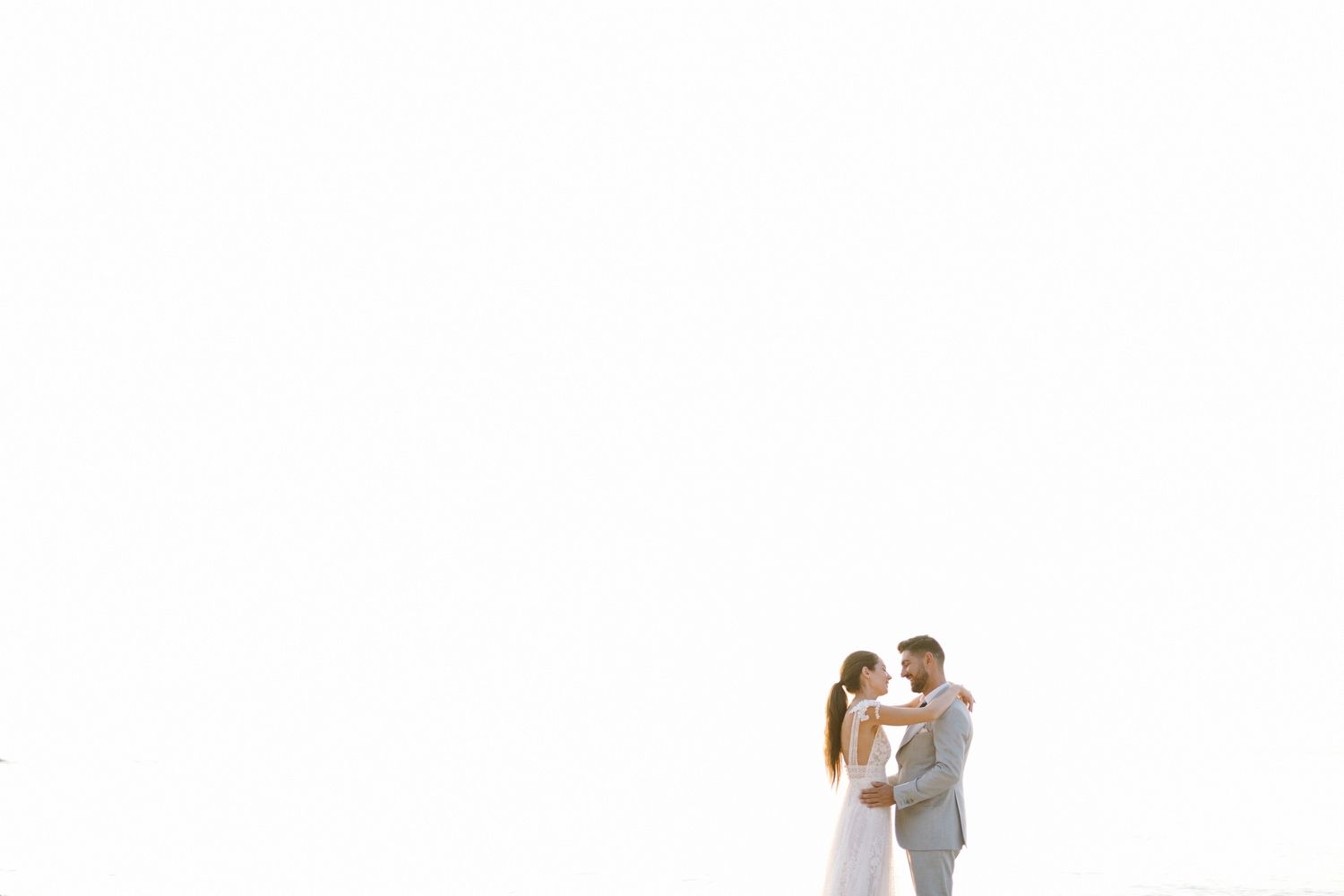 A minimalist wedding portrait against a white background captures an intimate moment between newlyweds.