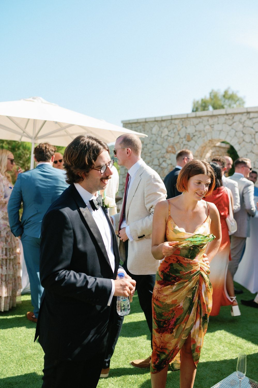Wedding guests enjoying outdoor cocktail reception on a sunny day.