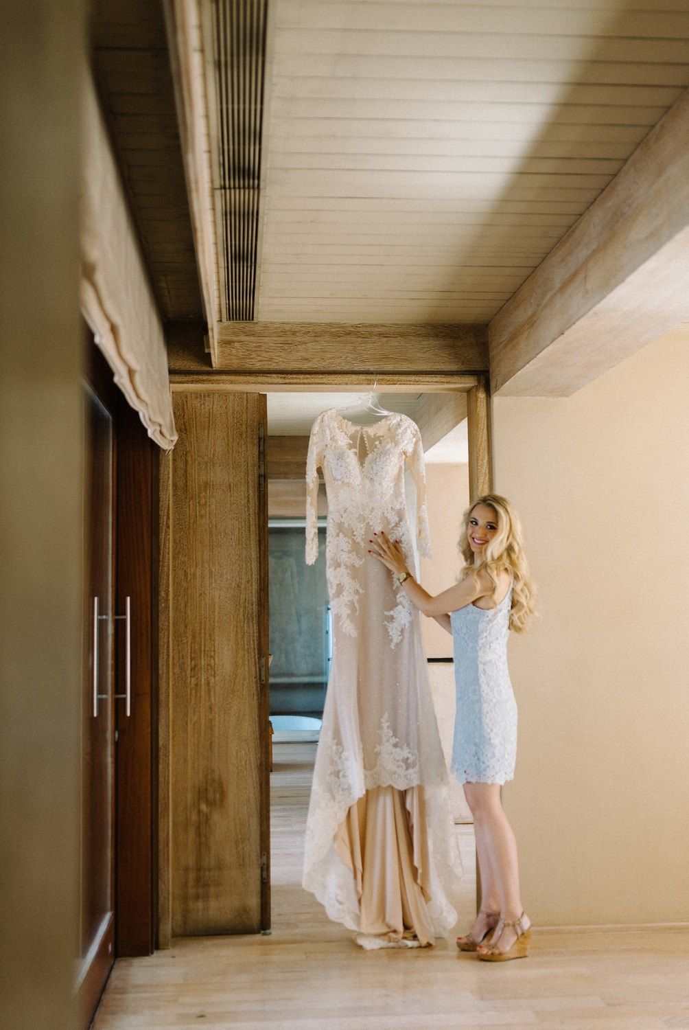 White wedding dress hanging in hallway being admired.