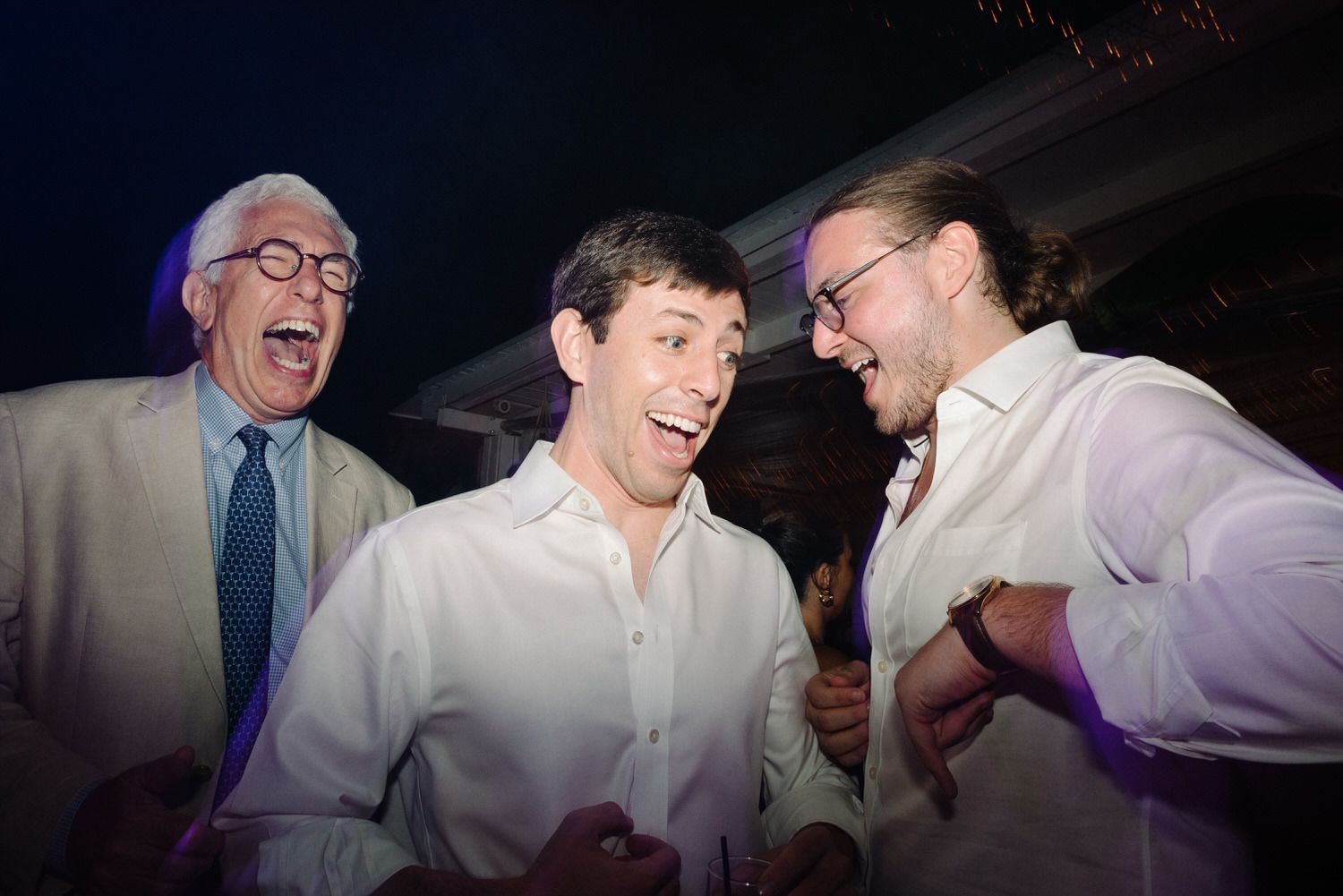 Three men laughing and sharing a joyful moment at what appears to be a celebration or party.