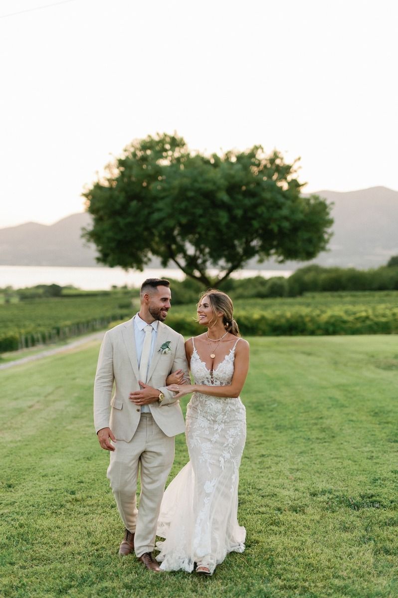 Newlyweds strolling together on green lawn with scenic mountain landscape.