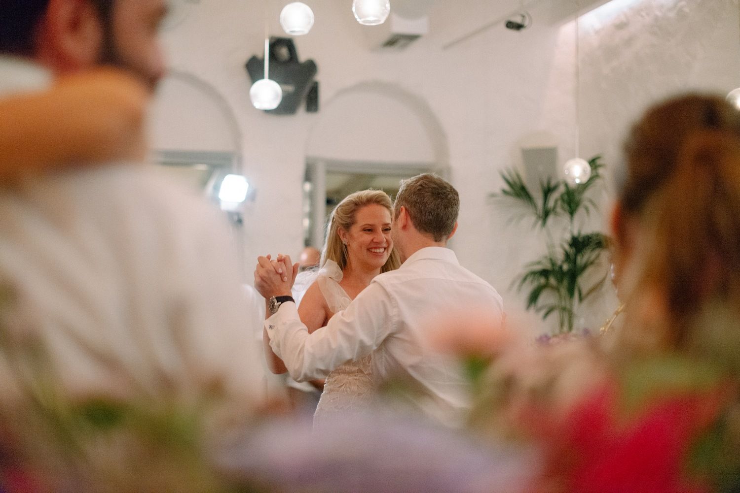 Couple shares a romantic moment during their wedding reception in a beautifully lit venue.