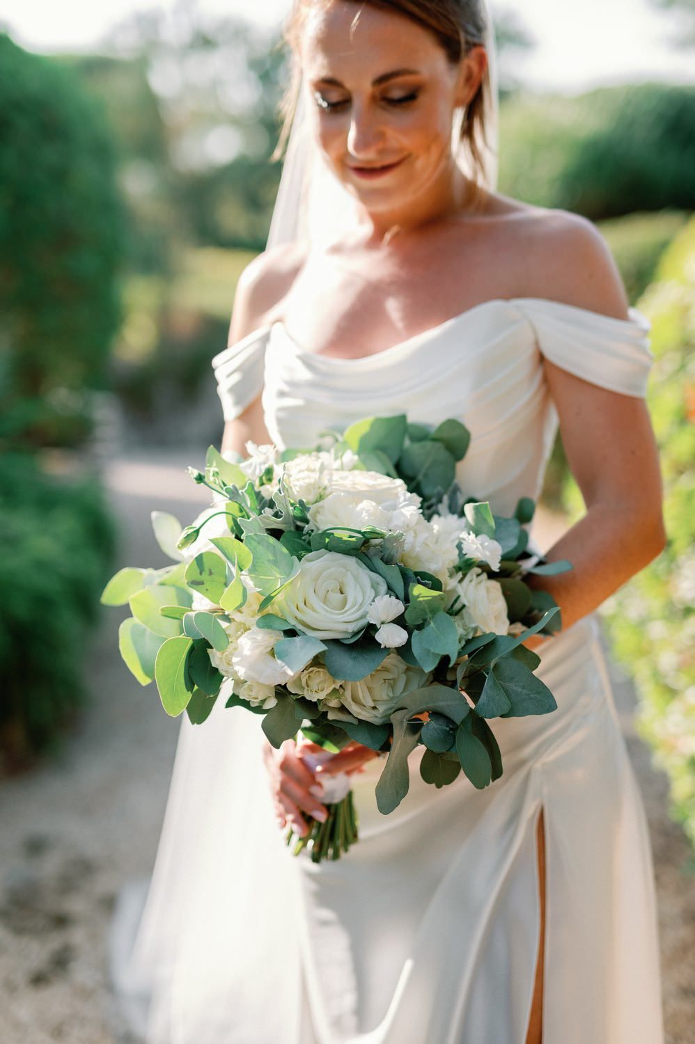 Elegant bridal bouquet of white roses and eucalyptus with flowing white wedding gown.