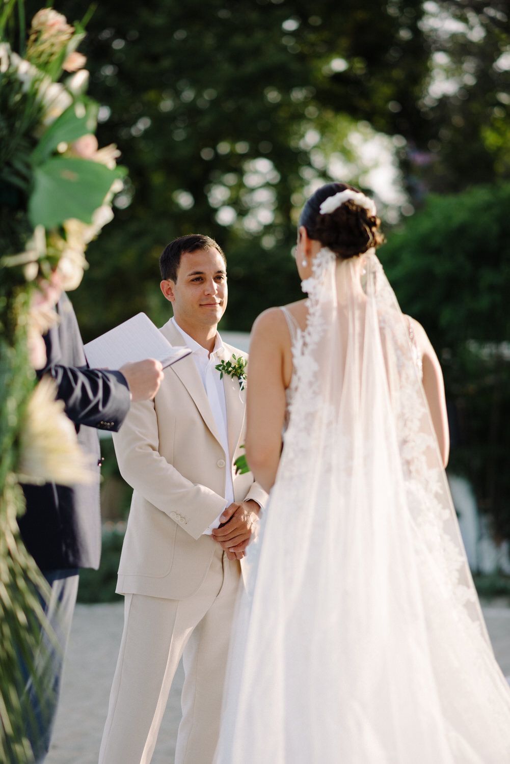 Couple exchanging vows during outdoor wedding ceremony with bride in flowing white dress.