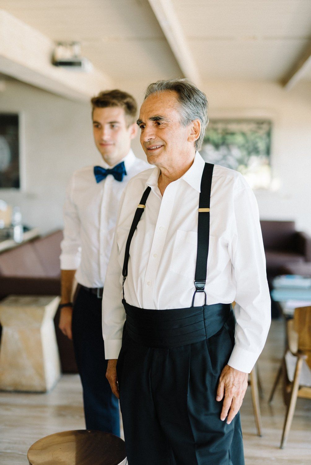 Two men in formal attire with suspenders and bow ties.