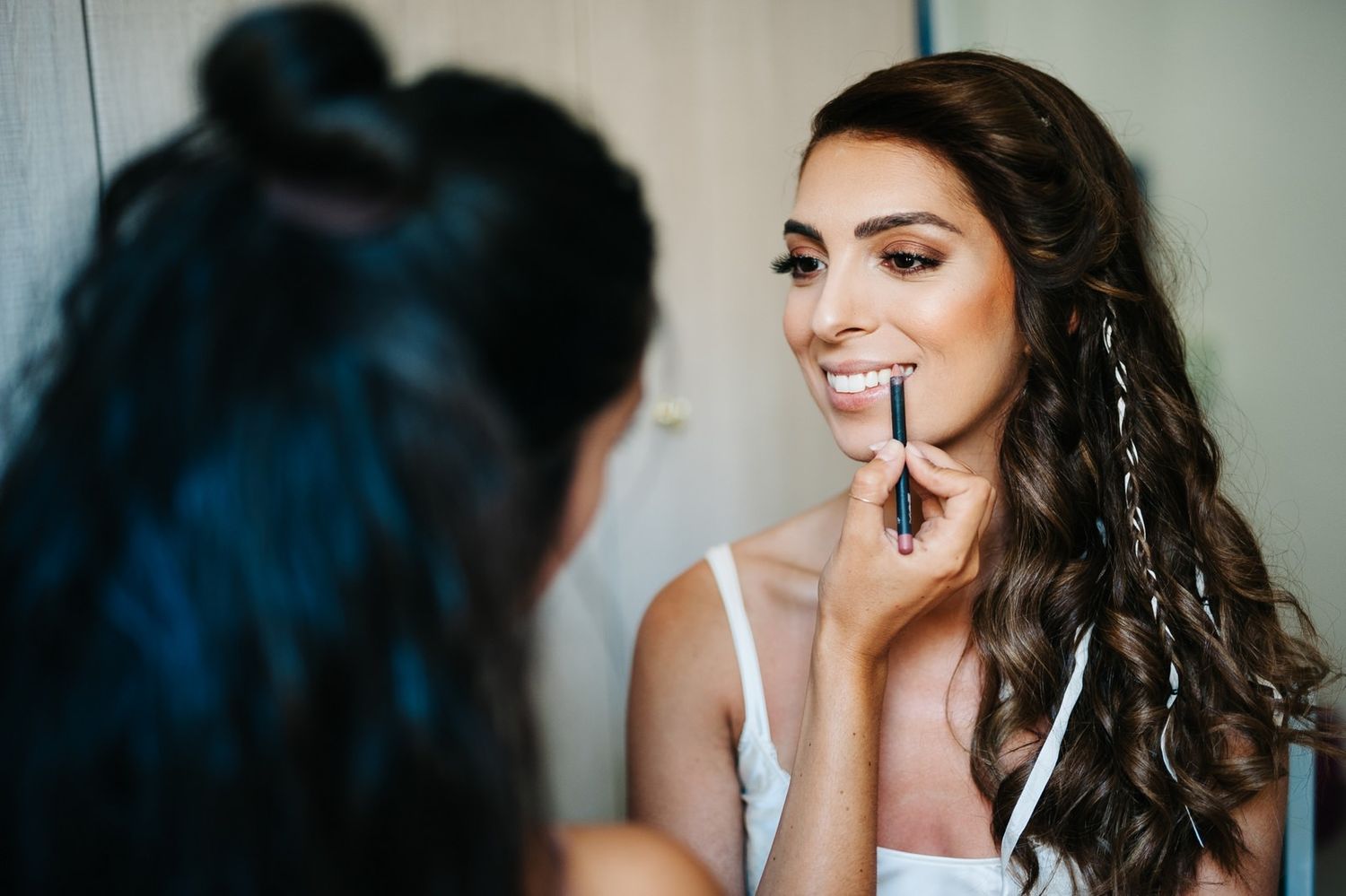 Makeup artist applying cosmetics during bridal preparation in natural light.
