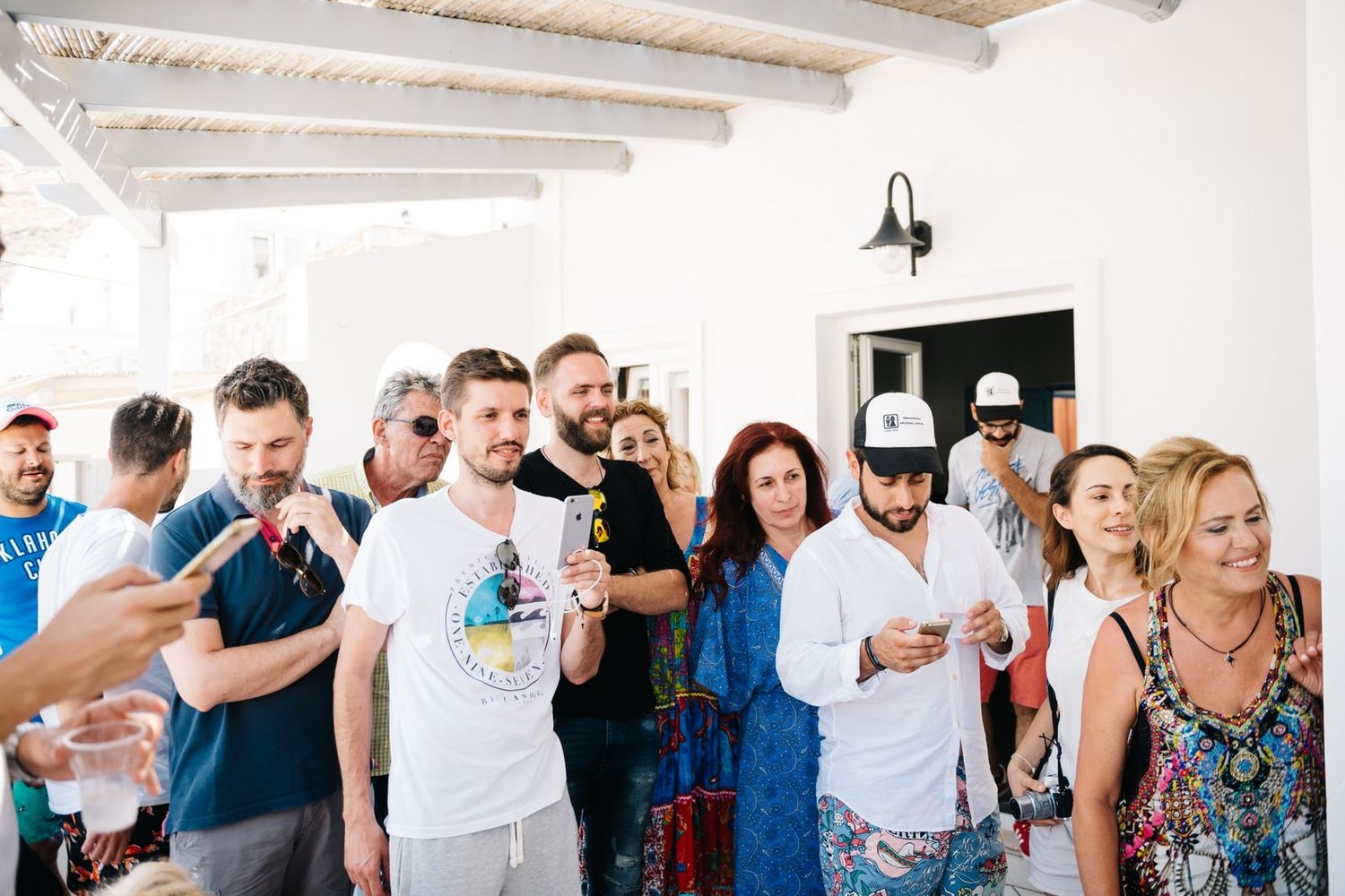 Group of people socializing at an informal party in a white-walled room.