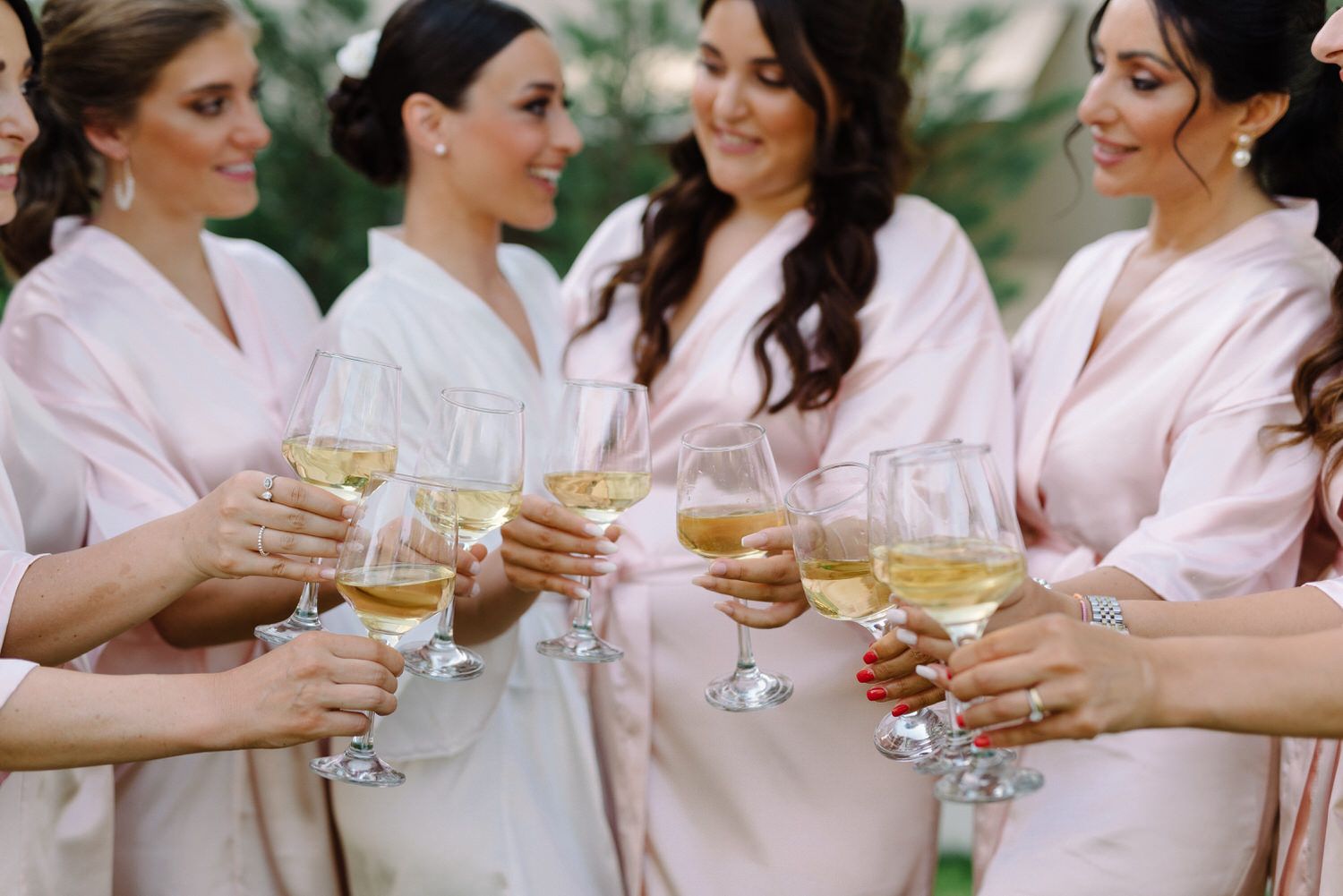 Wedding party members clink champagne glasses while wearing coordinated robes.