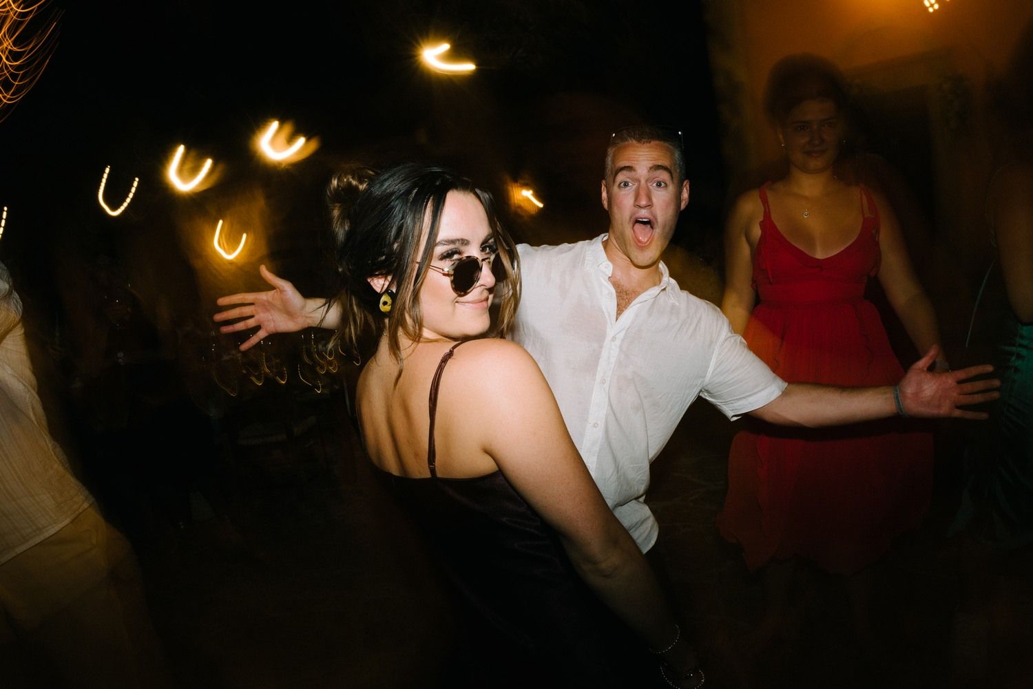 Dancers enjoying themselves under ambient lighting at a nighttime celebration.