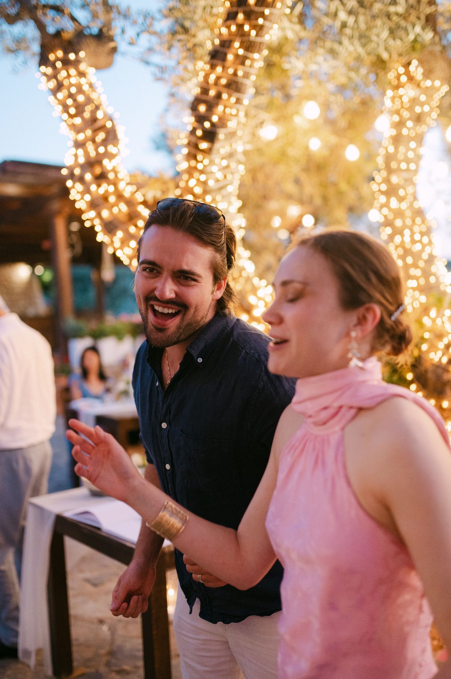A series of candid moments showing a couple enjoying a festive evening under string lights on an outdoor patio.