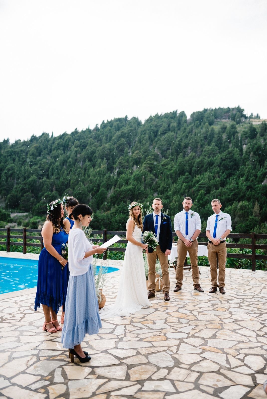 Wedding ceremony on stone patio with swimming pool and forested mountain views.