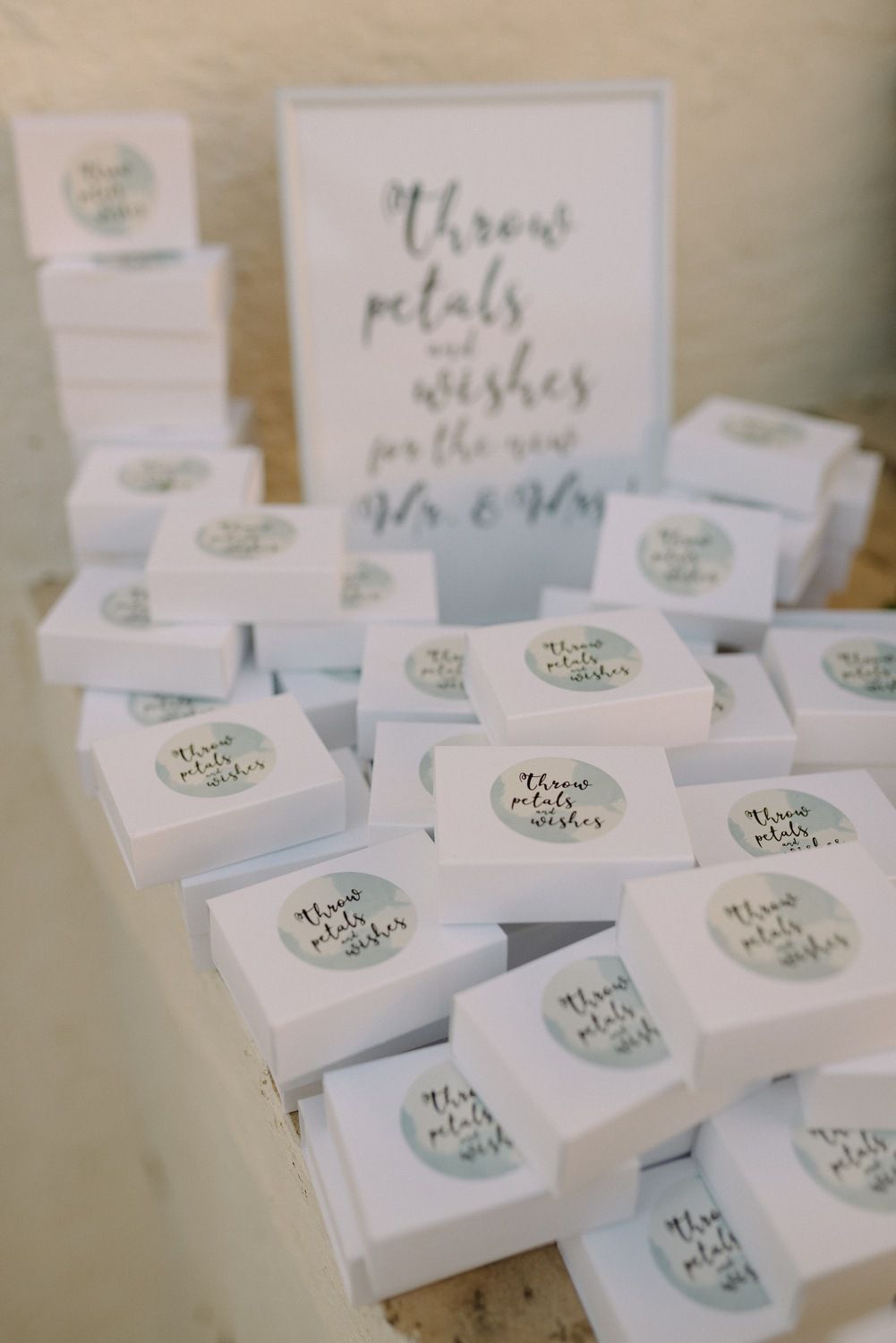 White wedding favor boxes with 'Throw petals' text arranged on display.