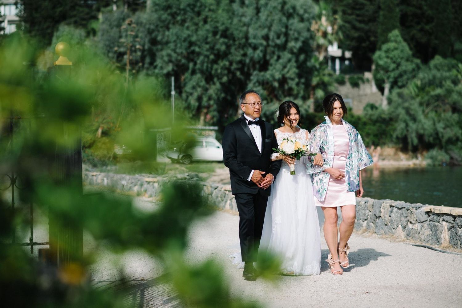 Wedding party posing together by a stone wall in a lush garden setting.