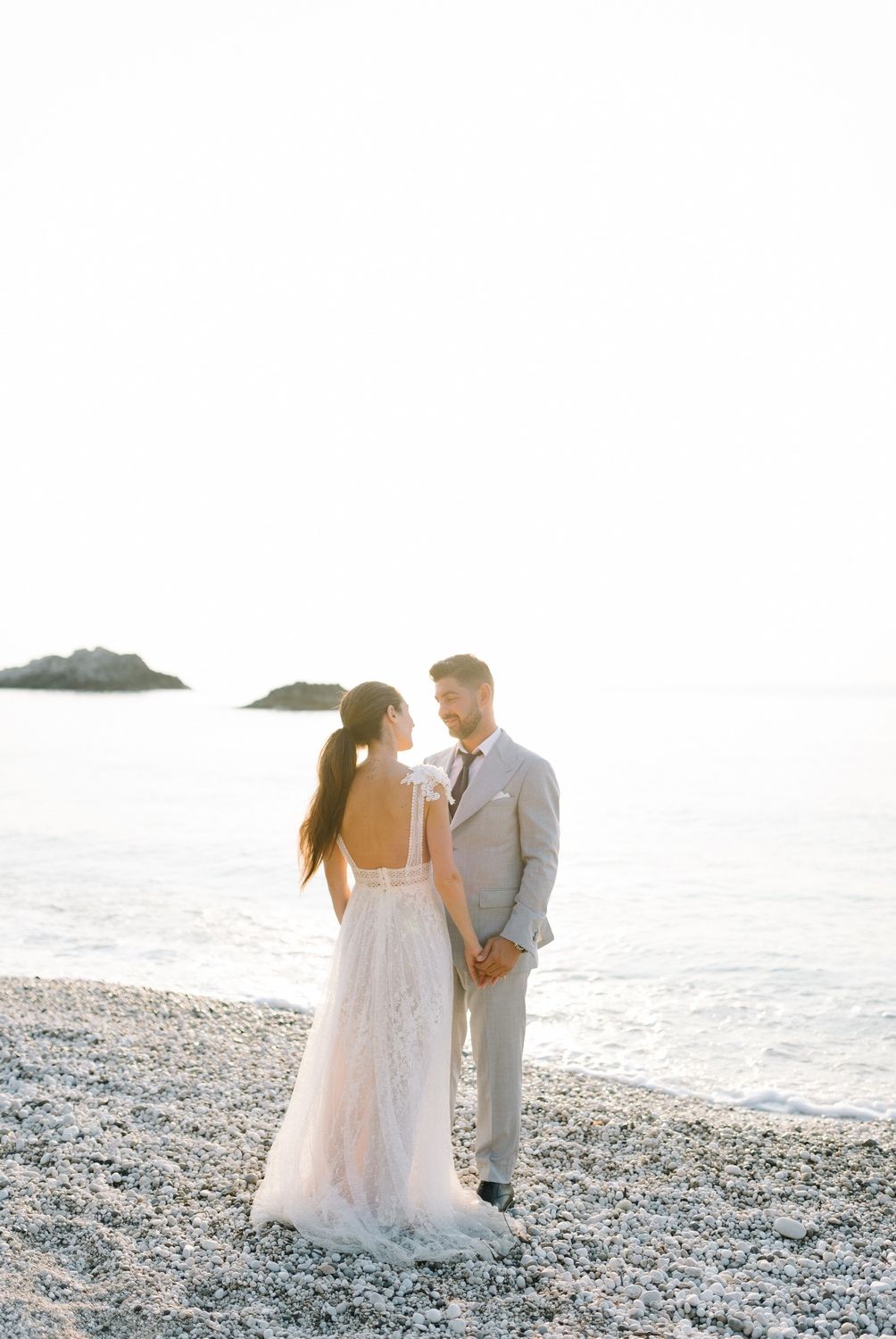 Romantic beachside wedding photo with couple standing together against bright ocean backdrop.