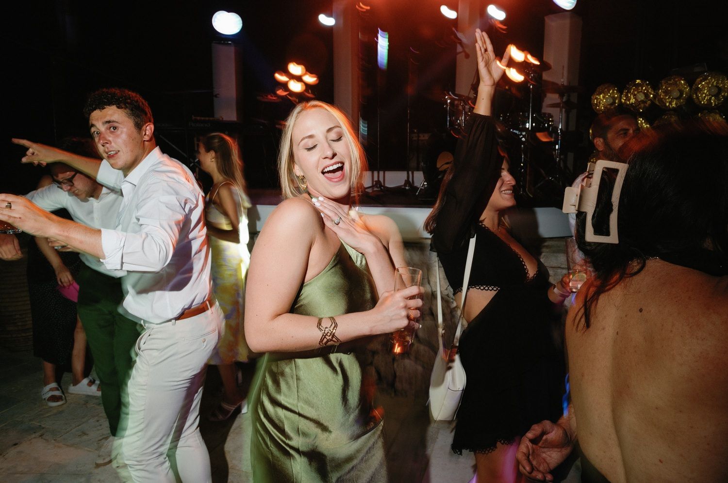 Energetic dancing and celebration at nighttime outdoor party with string lights.