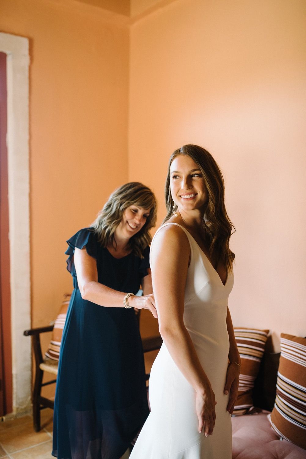 Wedding preparation scene showing a white bridal gown being adjusted in a warmly lit room.