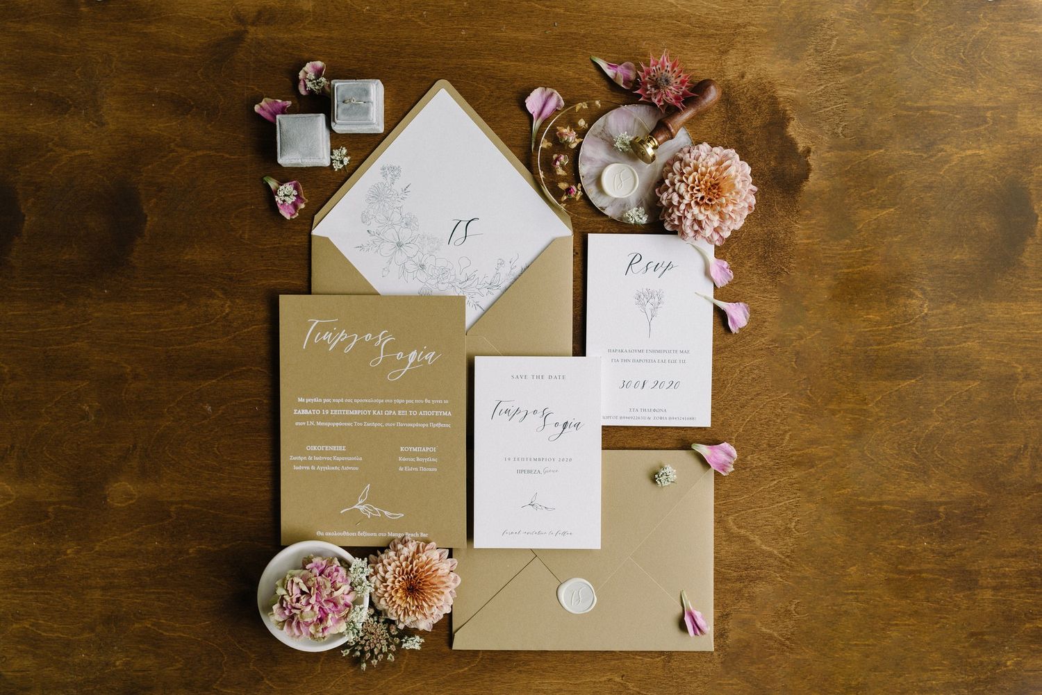 Wedding invitation suite with floral details and calligraphy on wooden surface.