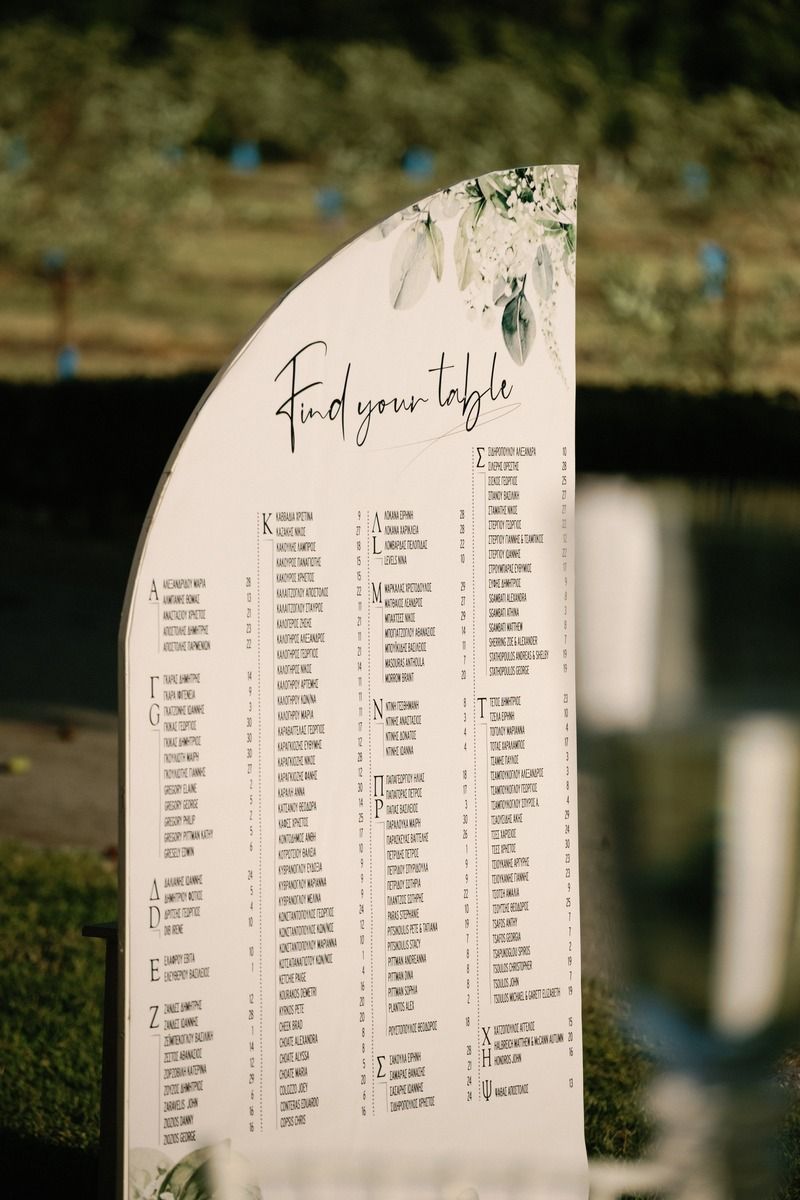 Semi-circular wedding seating chart display with elegant script lettering outdoors.
