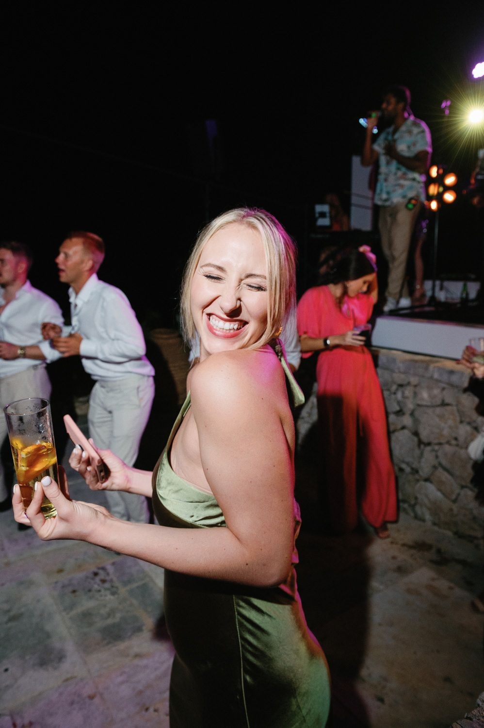 Party guest in green dress dancing joyfully at outdoor nighttime celebration.