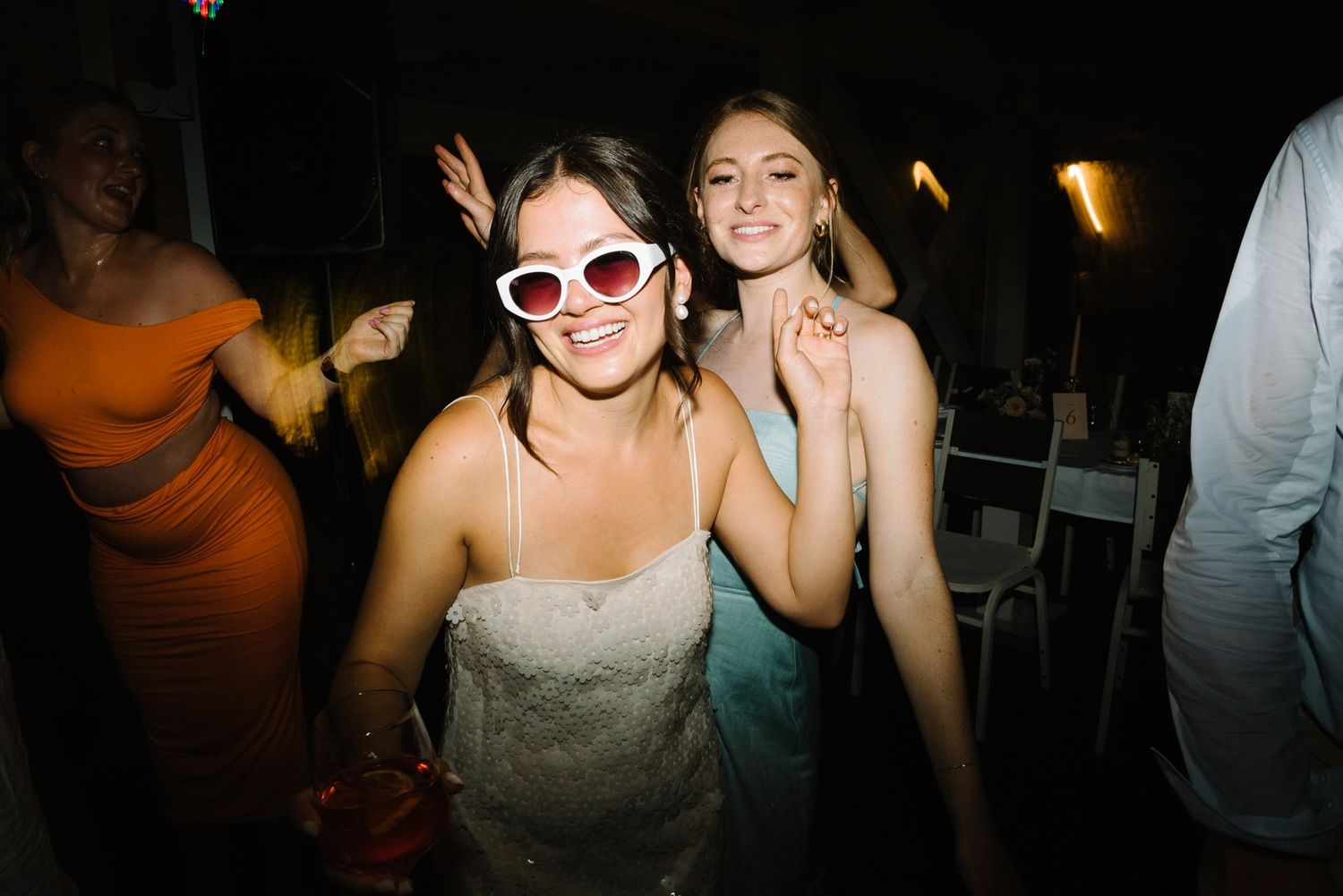 Party guests wearing stylish sunglasses dance together at a wedding reception.