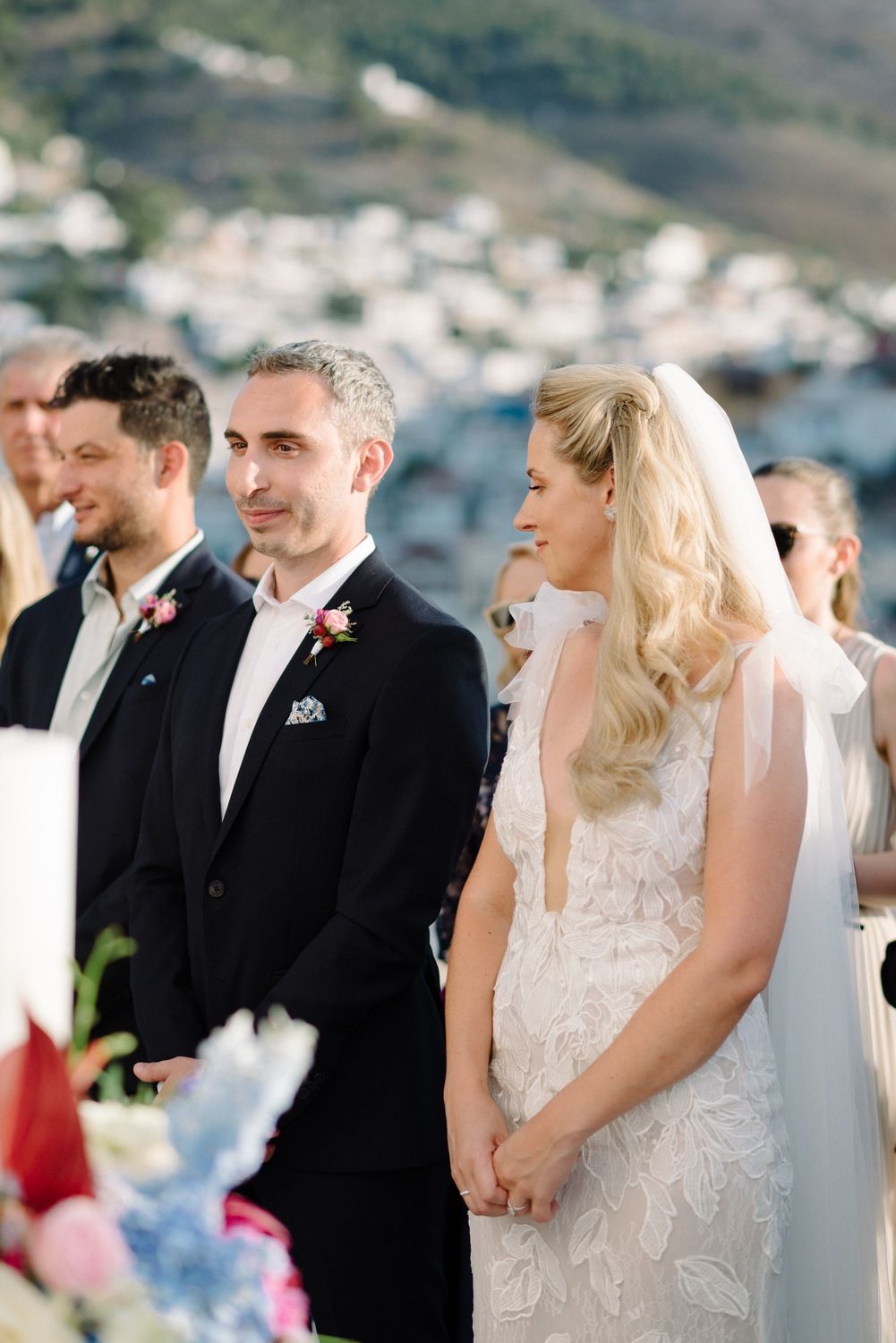 Wedding couple and attendants during ceremony with coastal Mediterranean scenery.