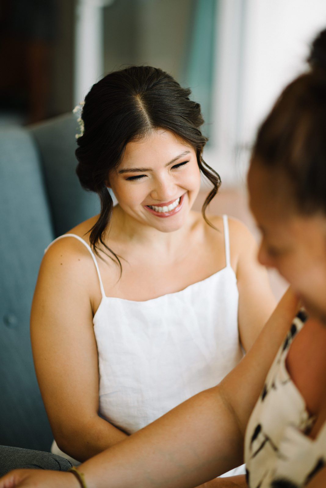Joyful bride in white dress smiles warmly during wedding preparations.