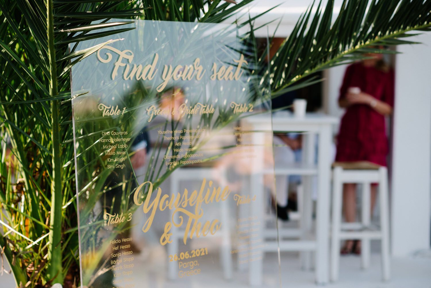 Wedding seating sign with palm fronds in tropical outdoor setting.