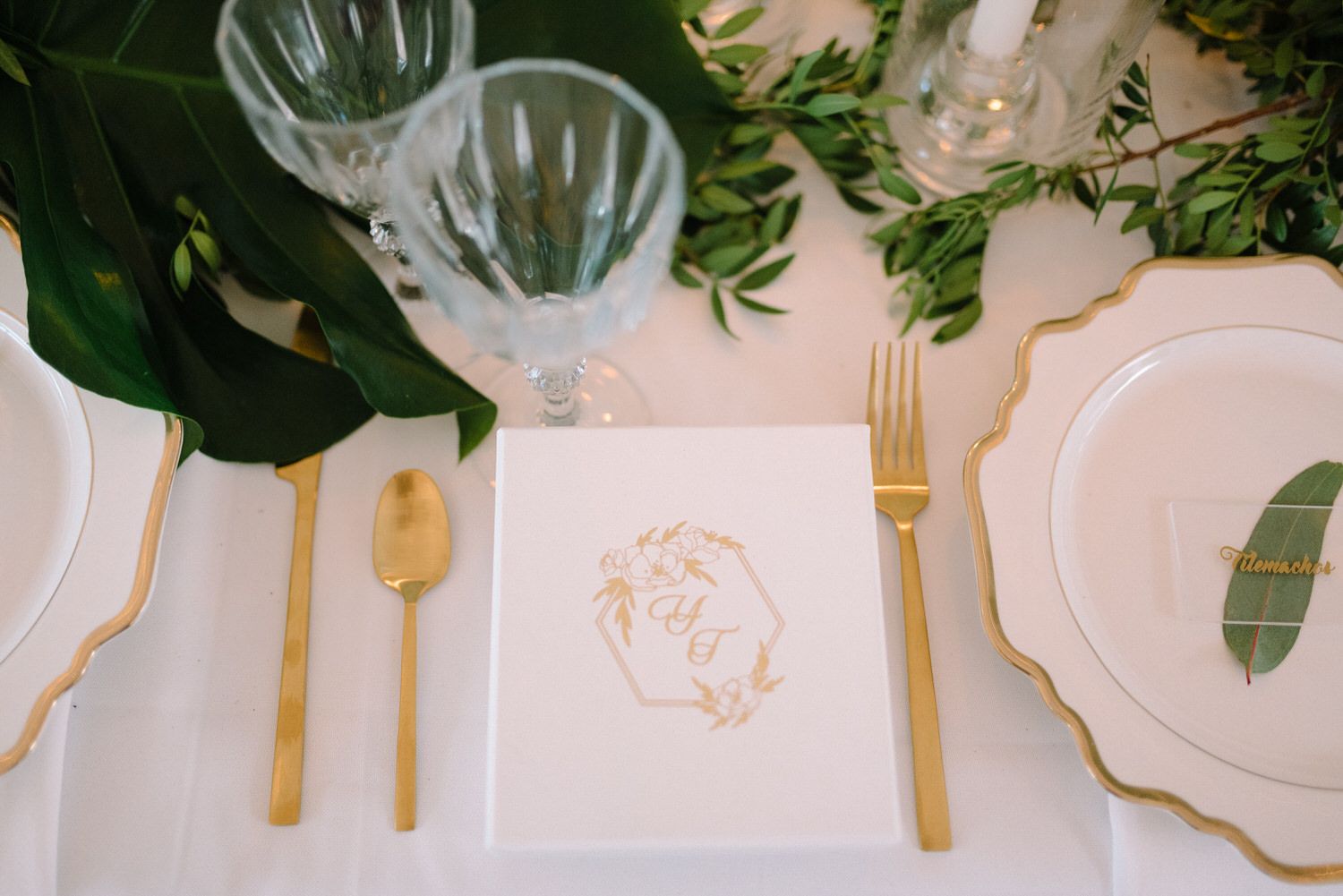 Elegant place setting with gold cutlery, crystal glassware, and a delicate gold-trimmed menu card.