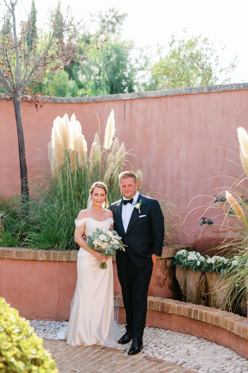 Wedding portrait in garden setting with pampas grass and terracotta walls.