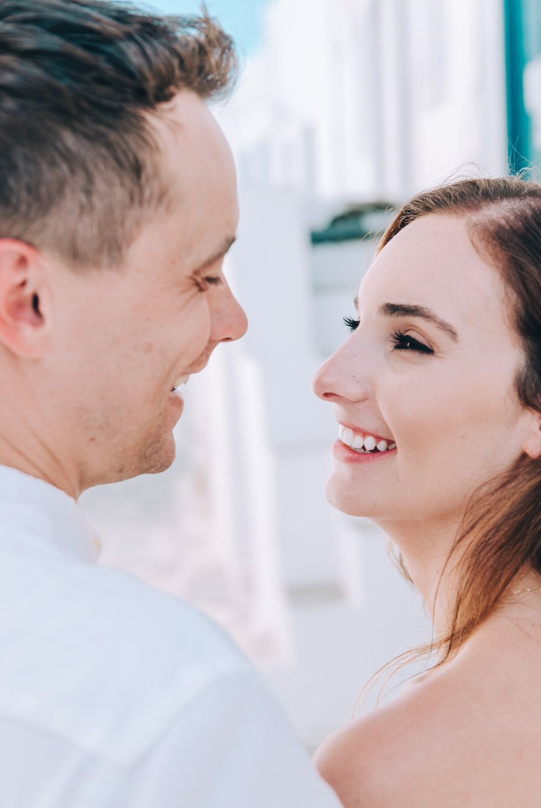 Close-up candid moment captured against white Mediterranean backdrop.