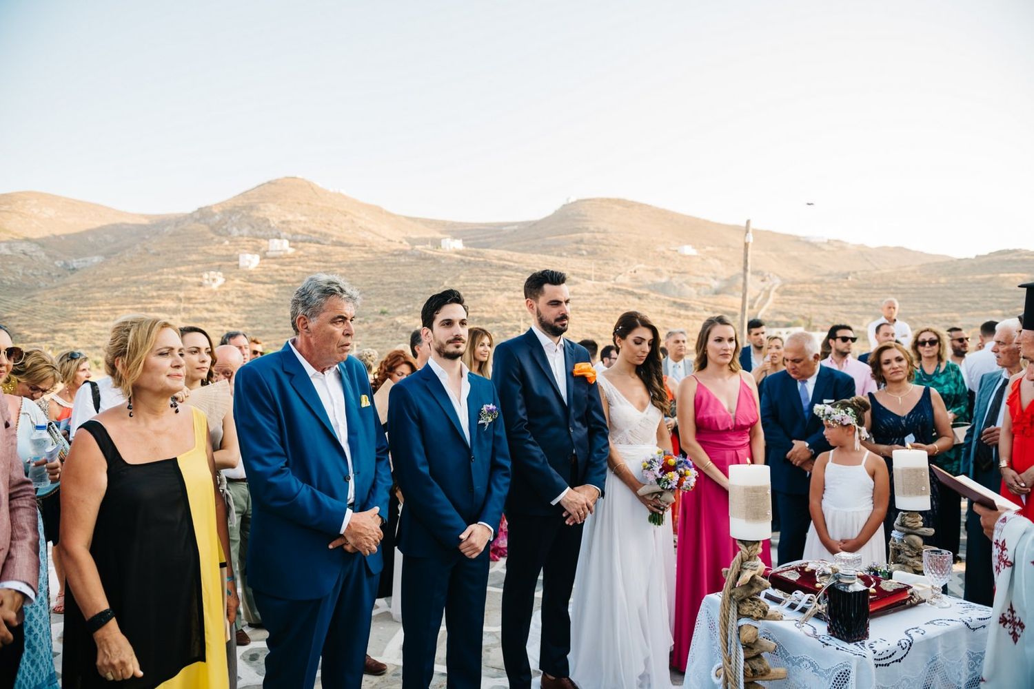 Wedding guests gathered on stone patio for ceremony with mountains in background.