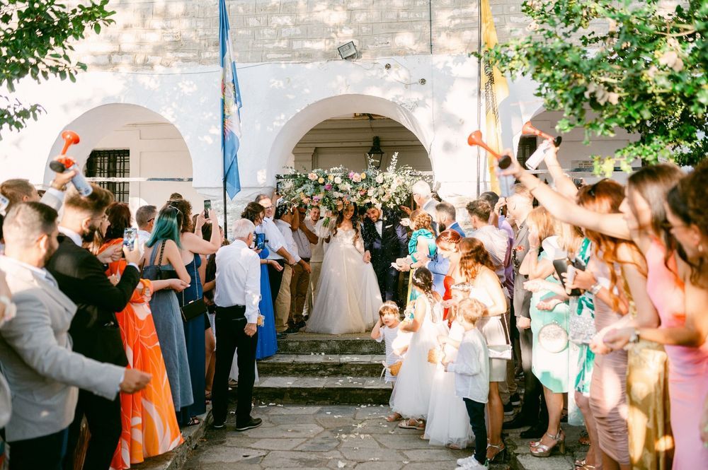 Wedding guests line up outside a stone building to throw confetti and celebrate during a joyful exit procession.