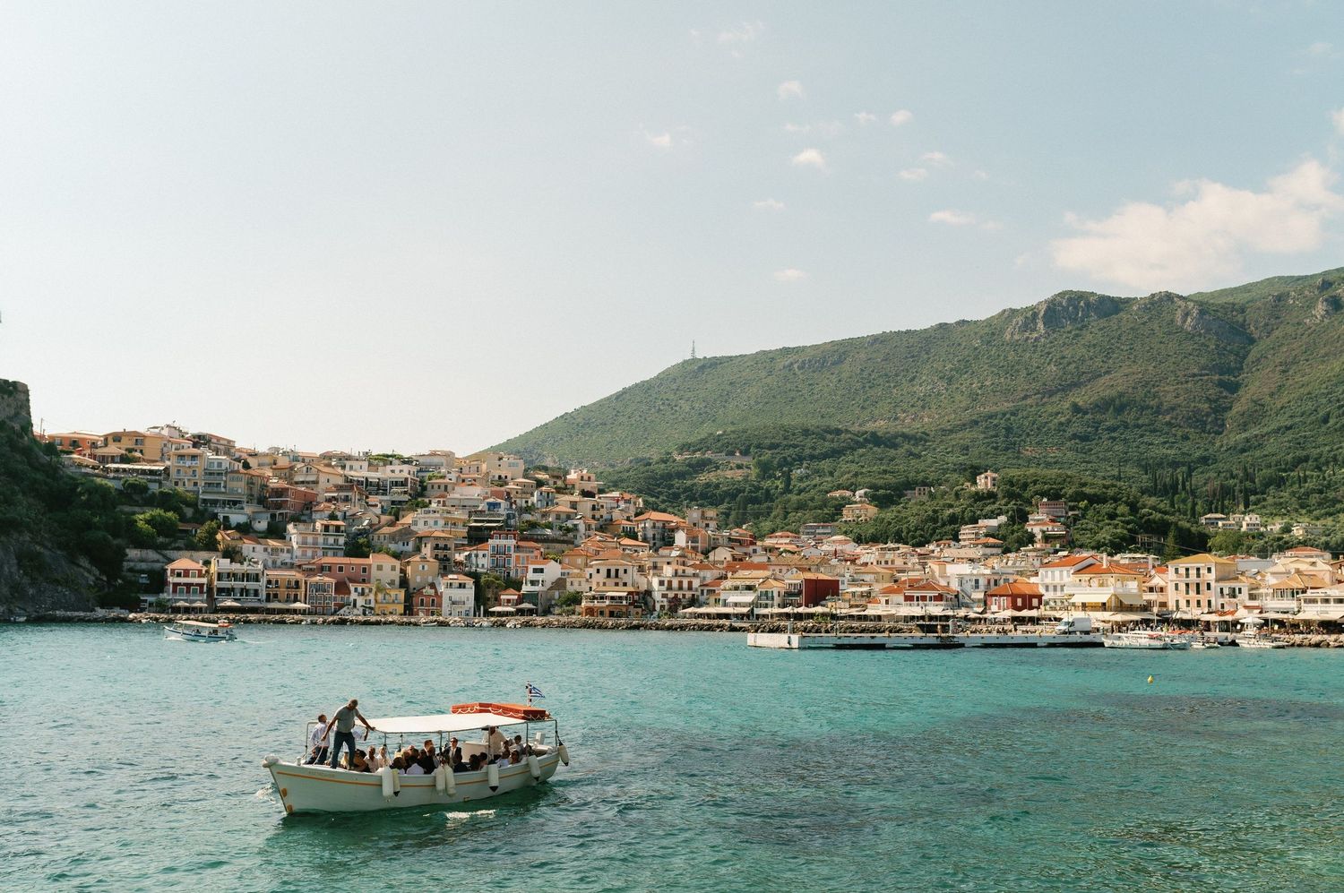 Panoramic view of Parga town with boats docked in the harbor and mountains in the background.