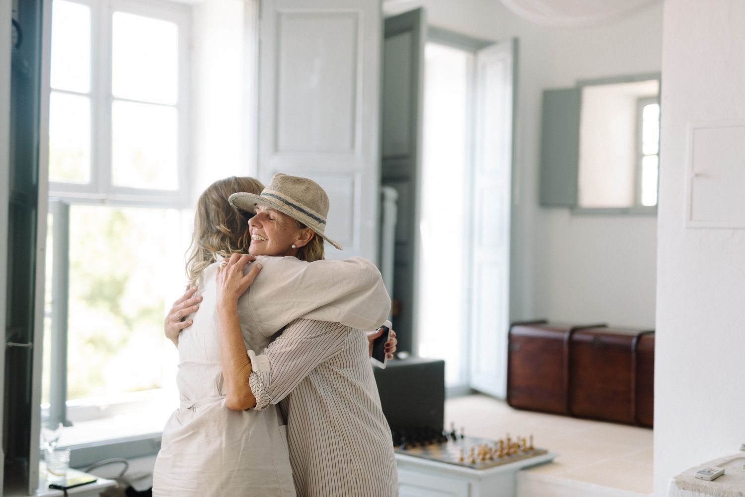 An emotional embrace between two people in a bright interior room with white walls.