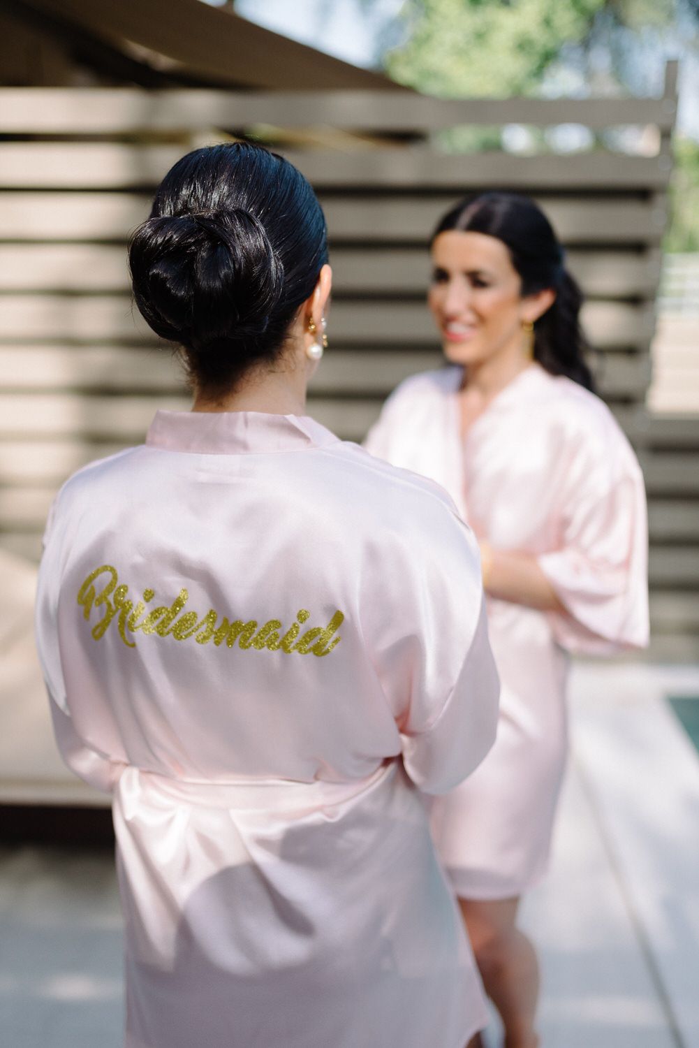 Pink satin robe with gold 'Bridesmaid' lettering shown from behind.