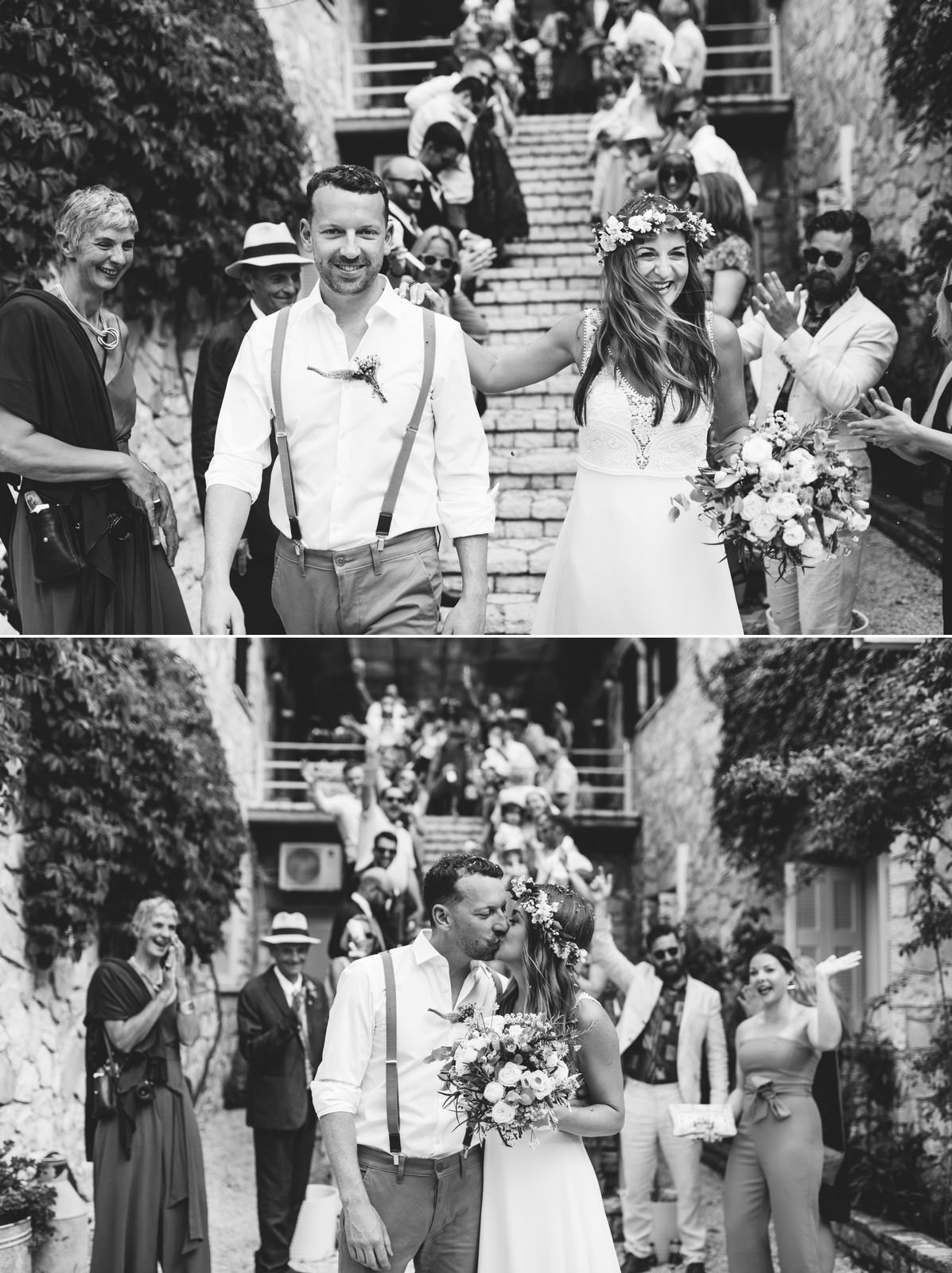 Newlyweds descend stone steps surrounded by joyful wedding guests in black and white photography.