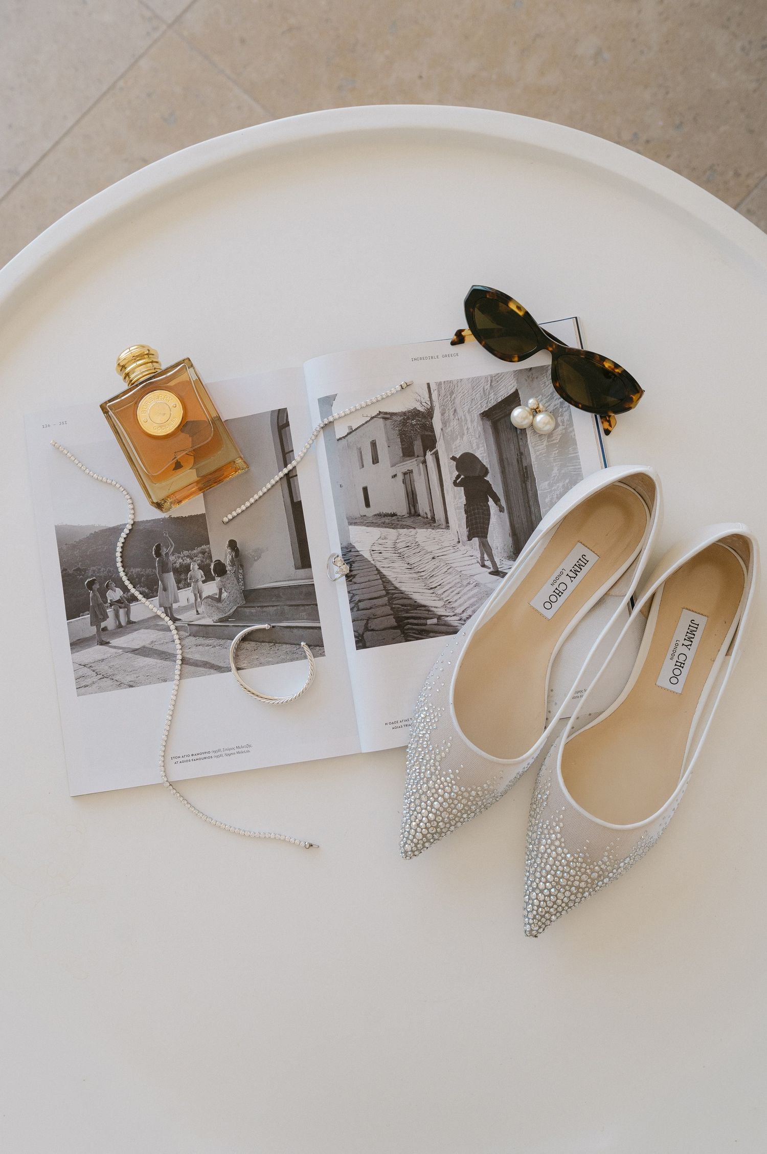 Stylish silver pointed-toe flats with crystal embellishments displayed alongside vintage black and white photographs.