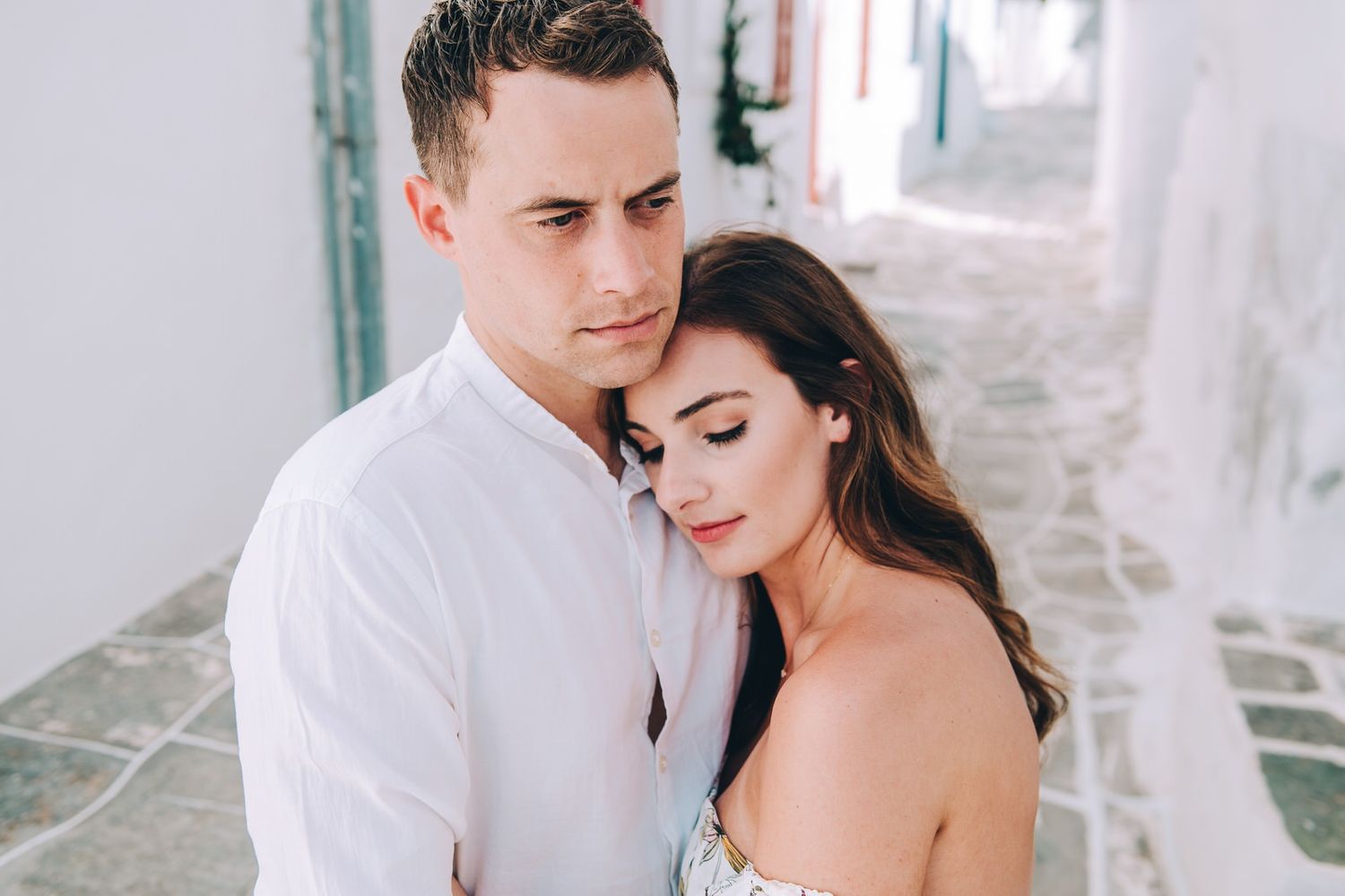 A tender embrace against white Mediterranean walls with soft lighting.