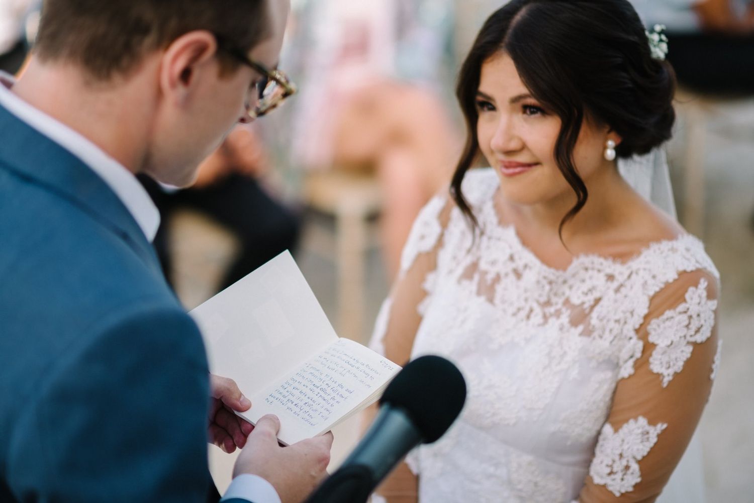 Groom reading vows from paper during outdoor wedding ceremony.