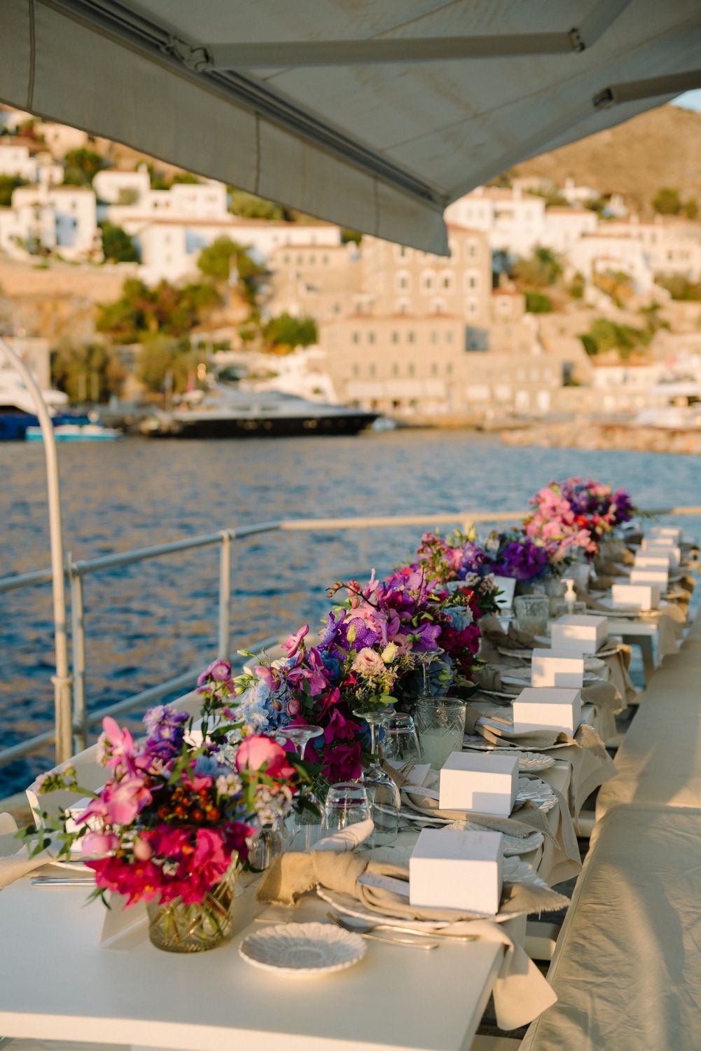 Waterfront dining table with stunning floral arrangements overlooking Mediterranean architecture and harbor.