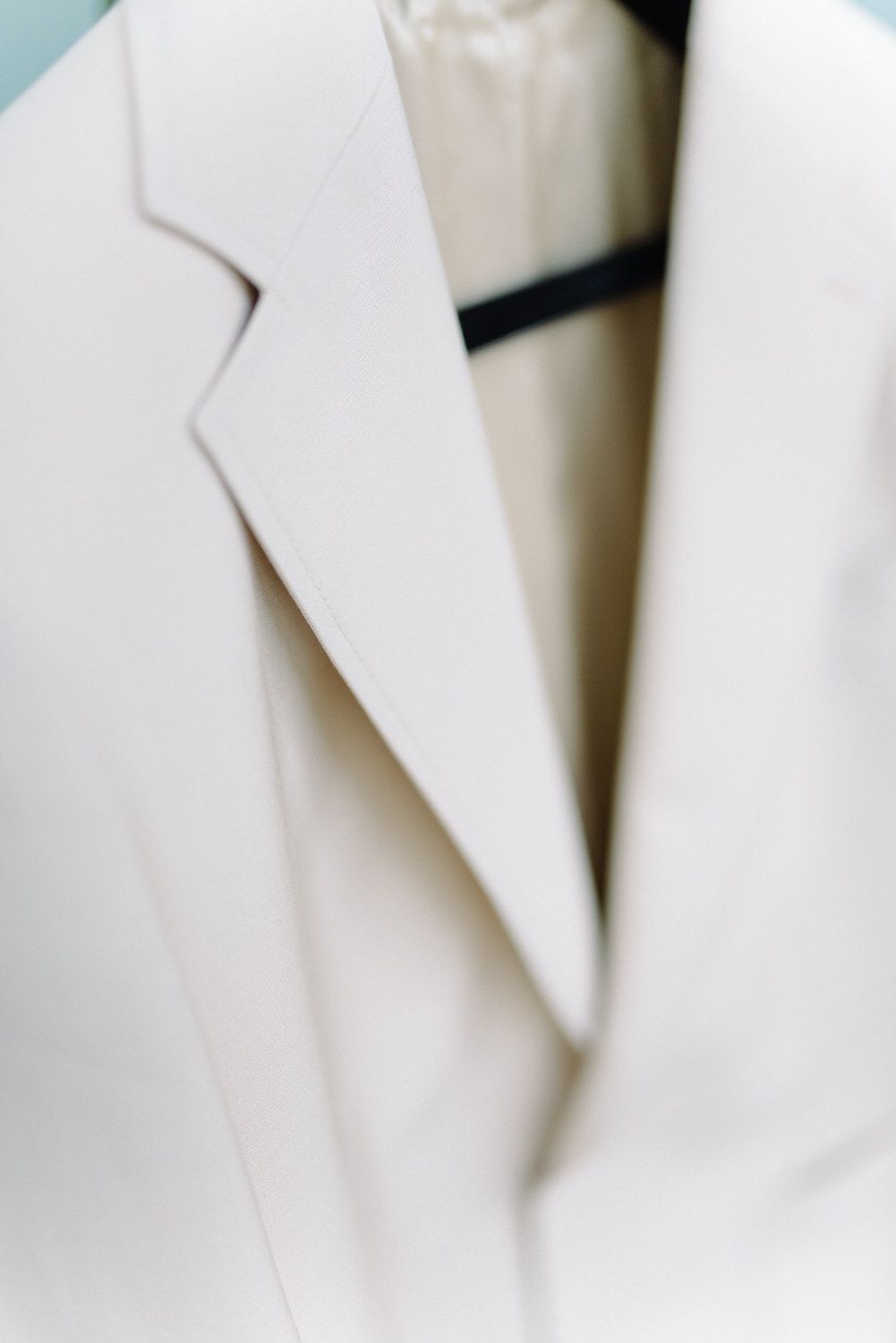 Close-up detail of white suit jacket lapel in soft natural light.