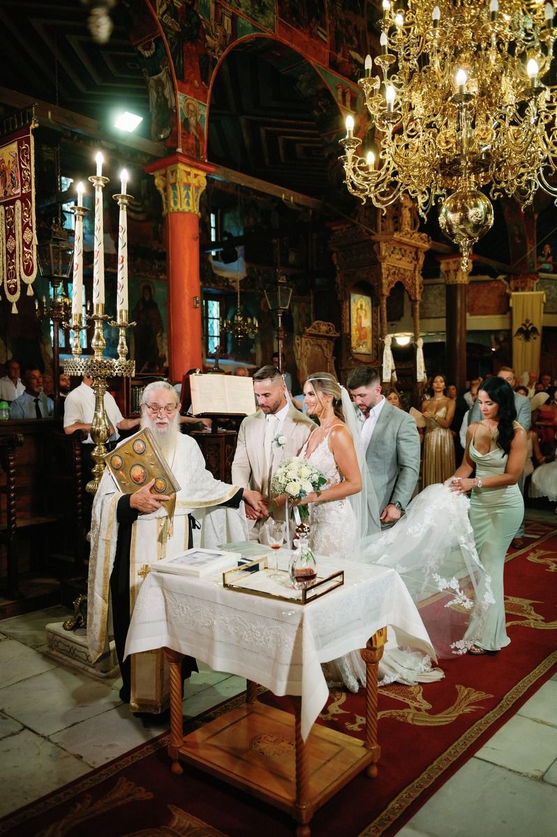 Traditional Orthodox wedding ceremony with priest at altar under ornate chandelier.