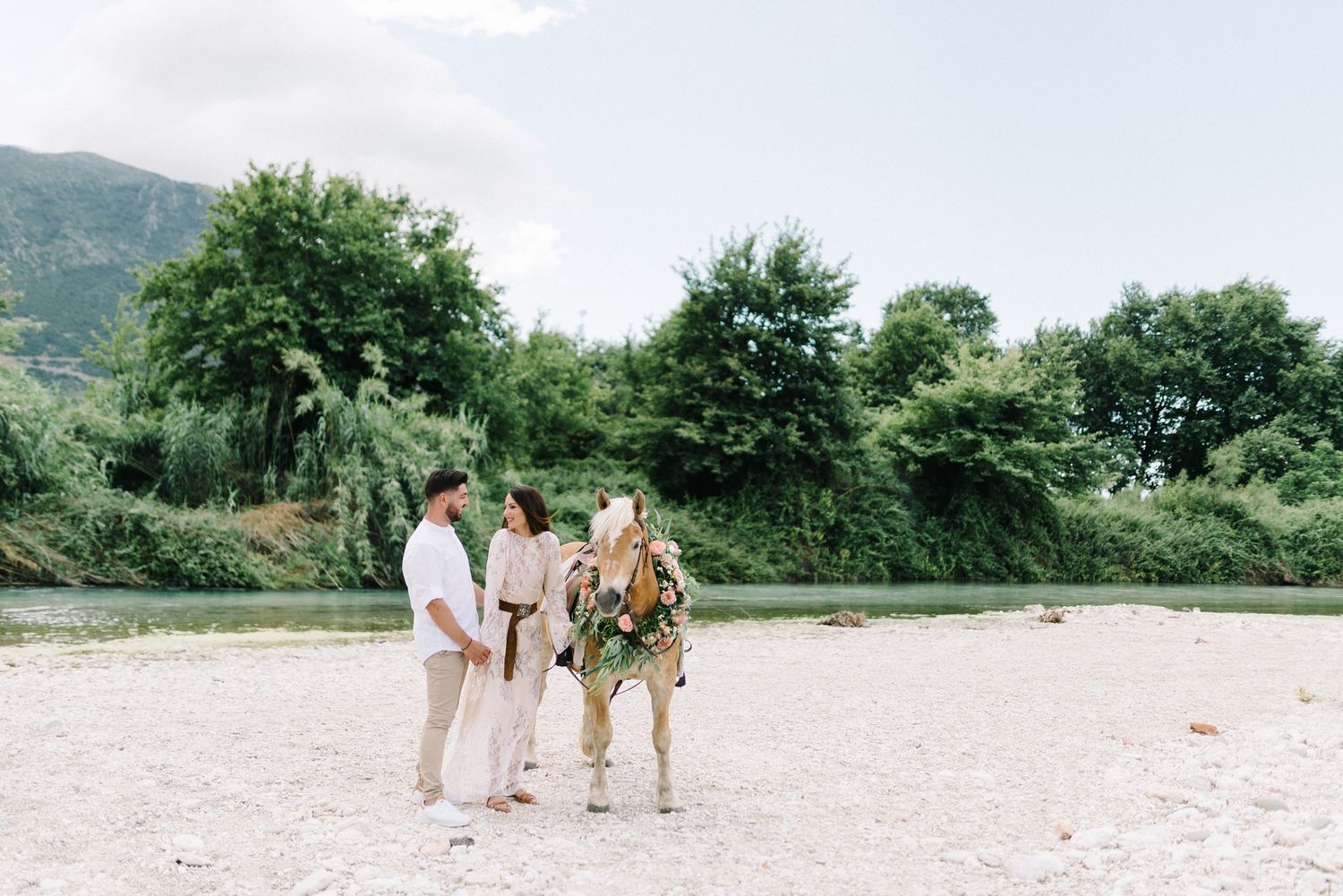 Small wedding ceremony group gathered on a beach with mountains in background.